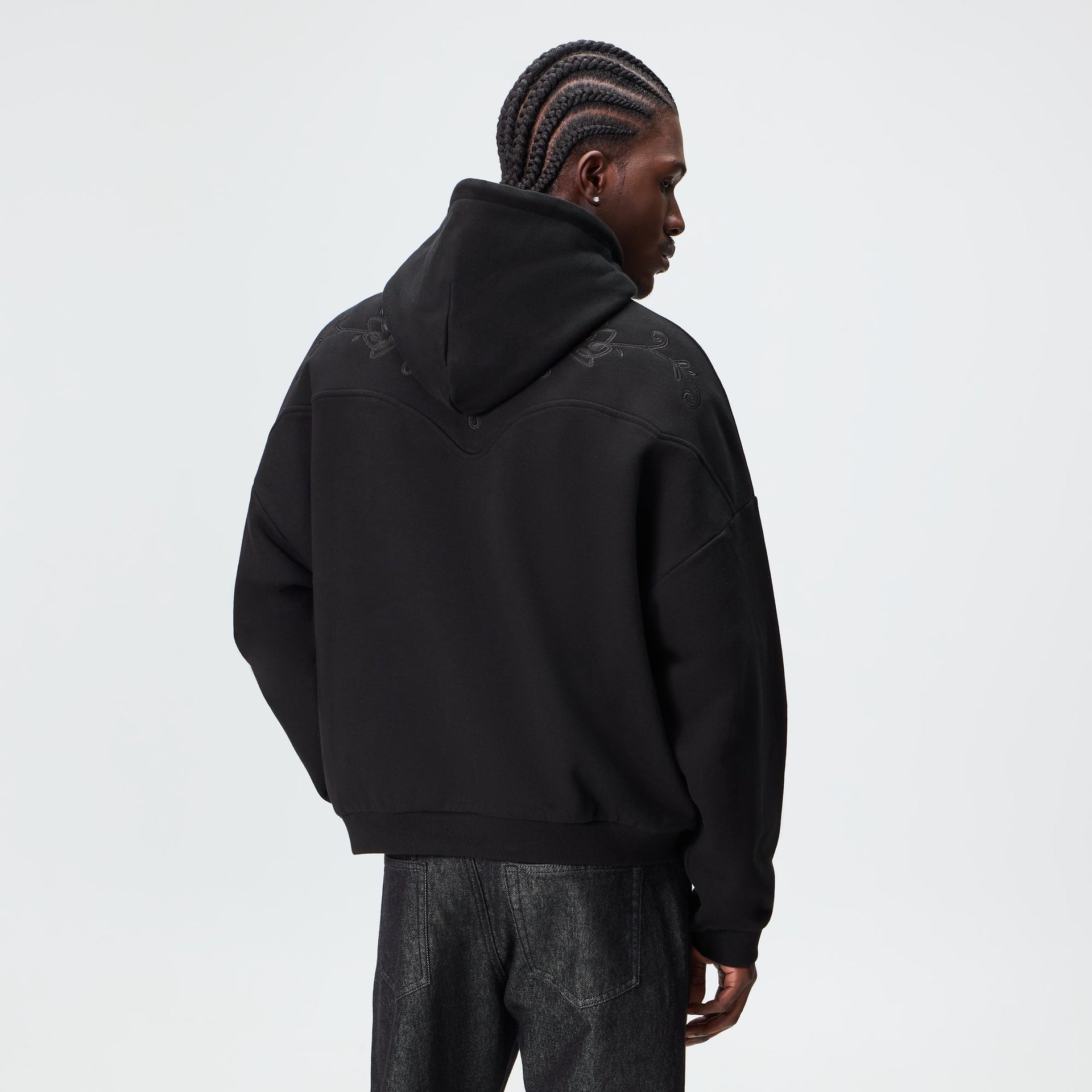 Man wearing the Kith Heritage Filigree Braxton hoodie in black, back three-quarter view