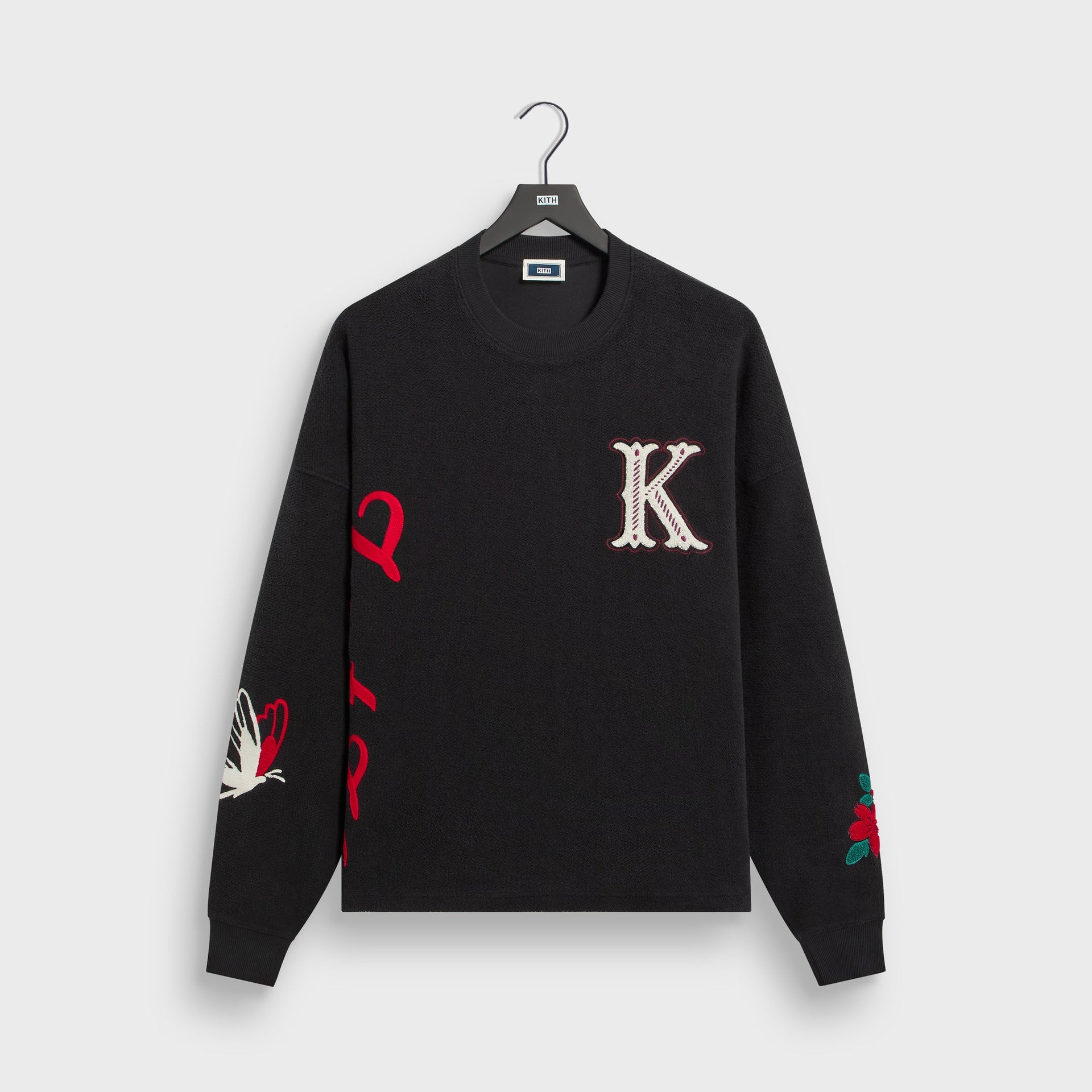 Kith Varsity Lawson crewneck in black with chenille K patch and red Just Us sleeve embroidery, front flat lay