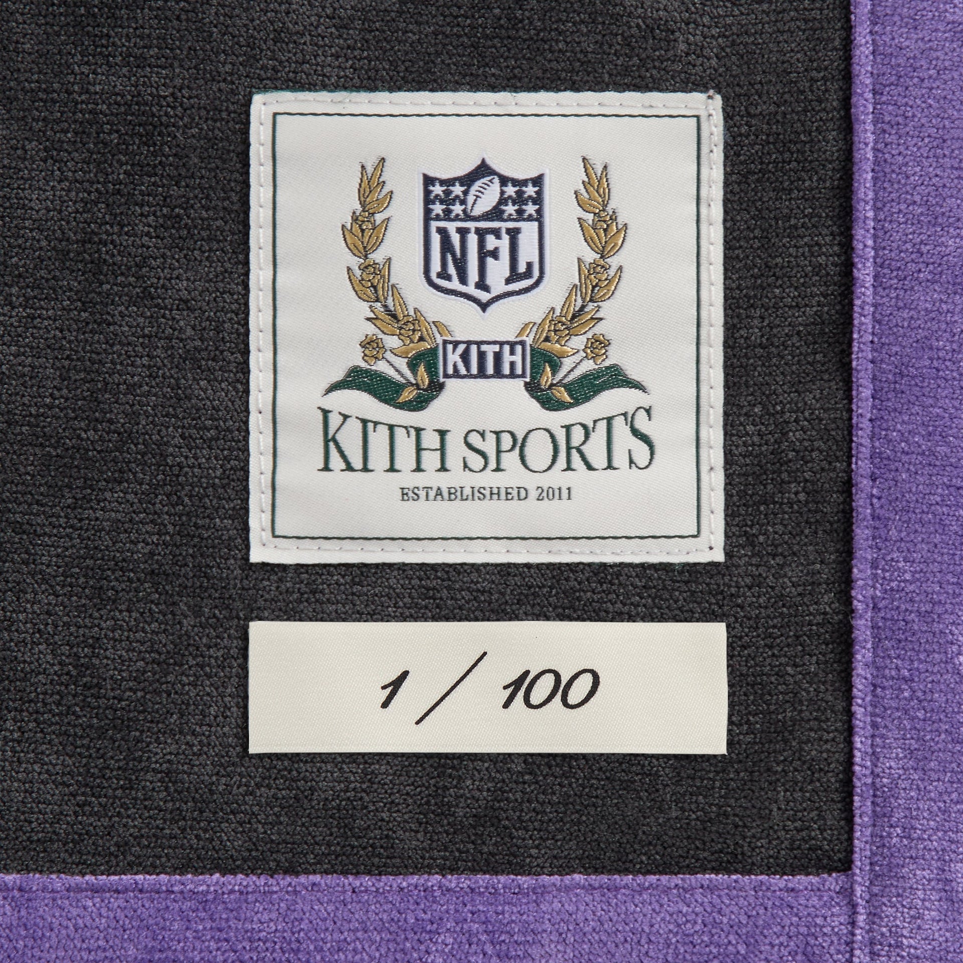 Close-up of the Kith Sports NFL woven label and 1 of 100 numbering tag on the Ravens Leon shirt