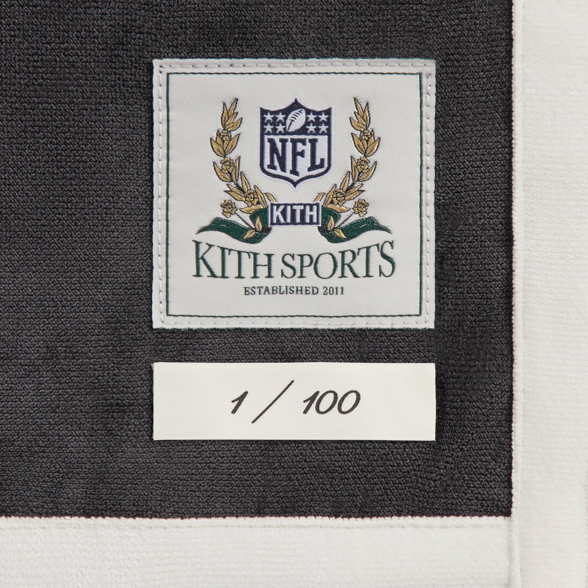 Close-up of the Kith Sports NFL woven label and 1 of 100 numbering tag on the Falcons Leon shirt