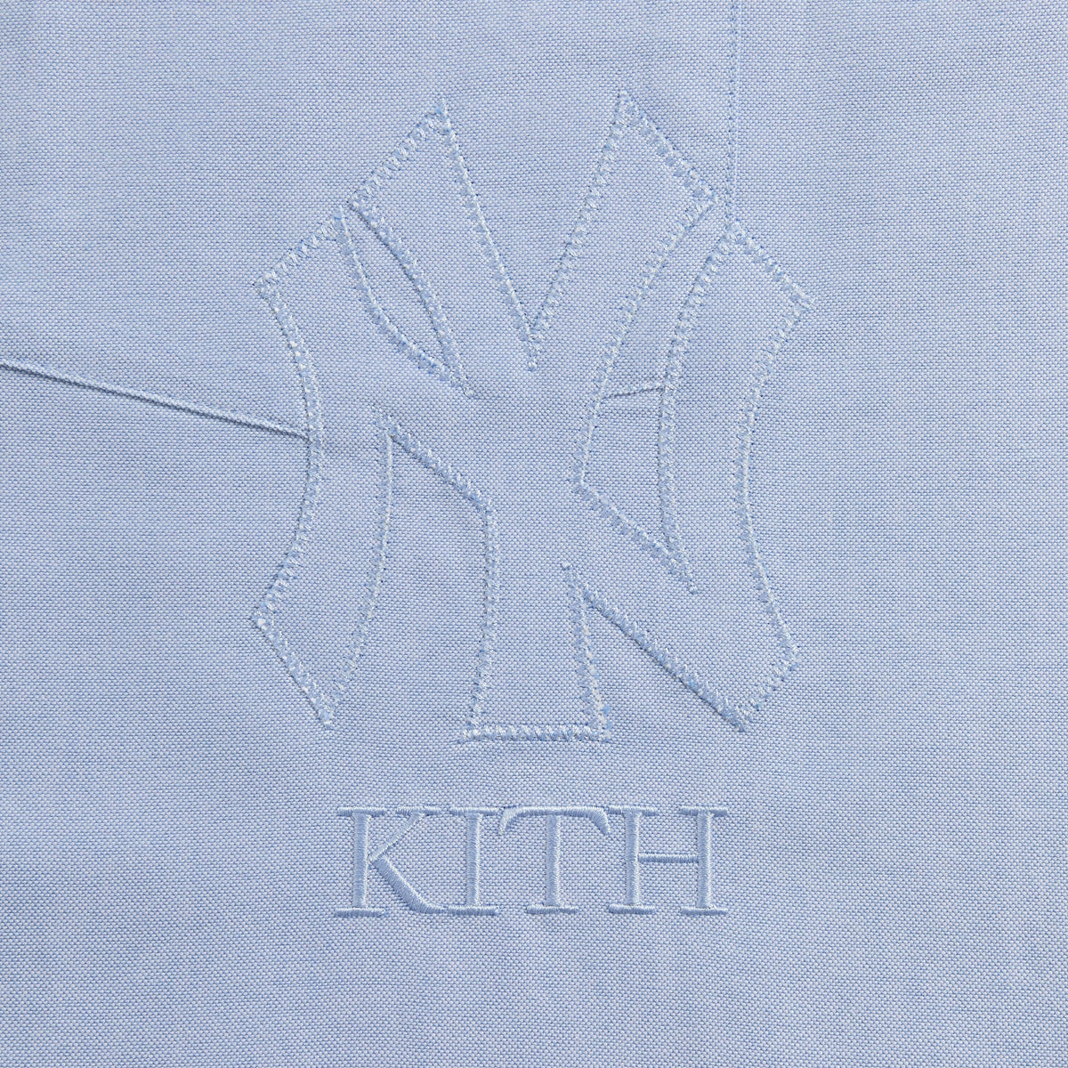 Close-up of embroidered NY Yankees and Kith logo on light blue Oxford Deon overshirt chest pocket