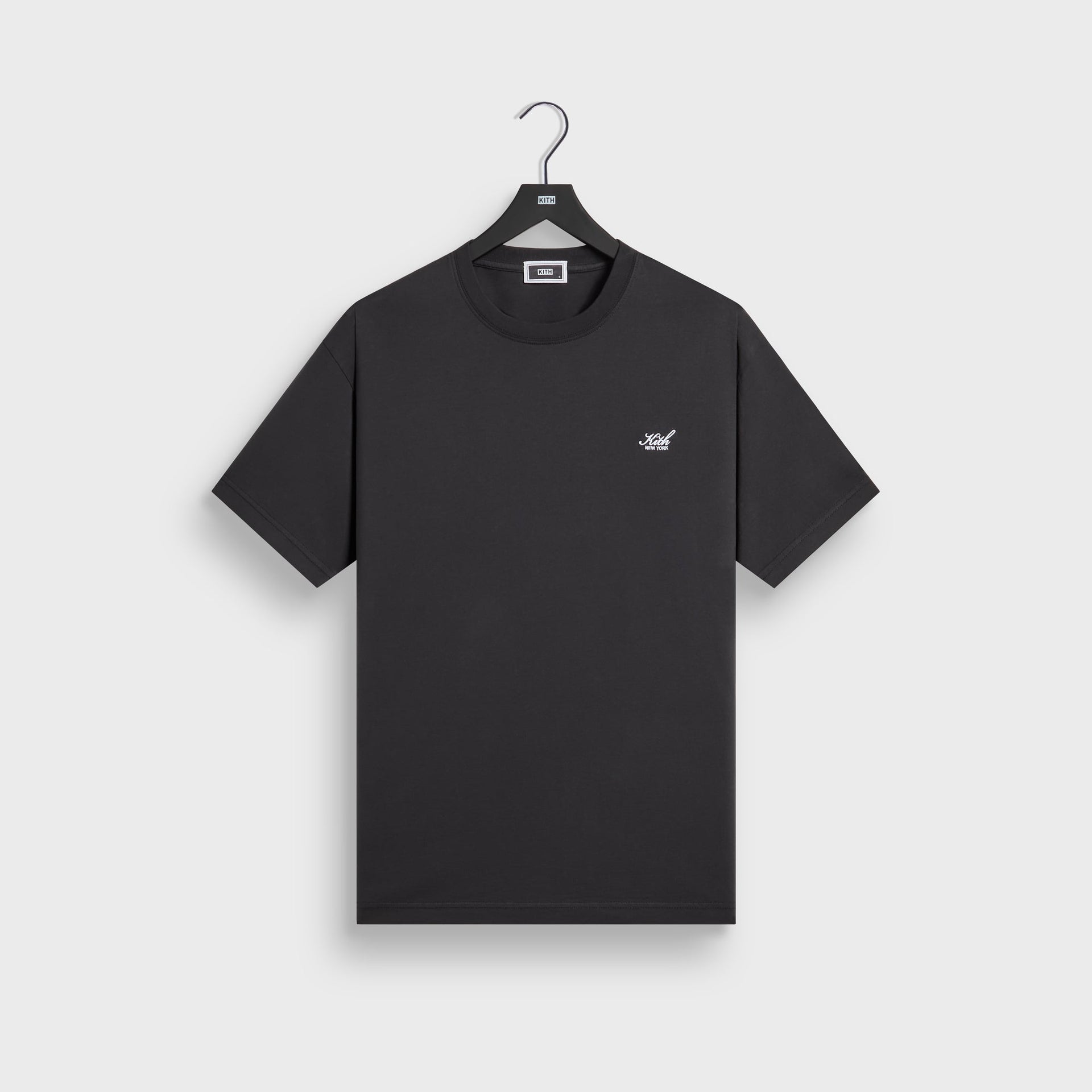 Kith LAX tee in black cotton with small crest chest logo, front flat lay on hanger