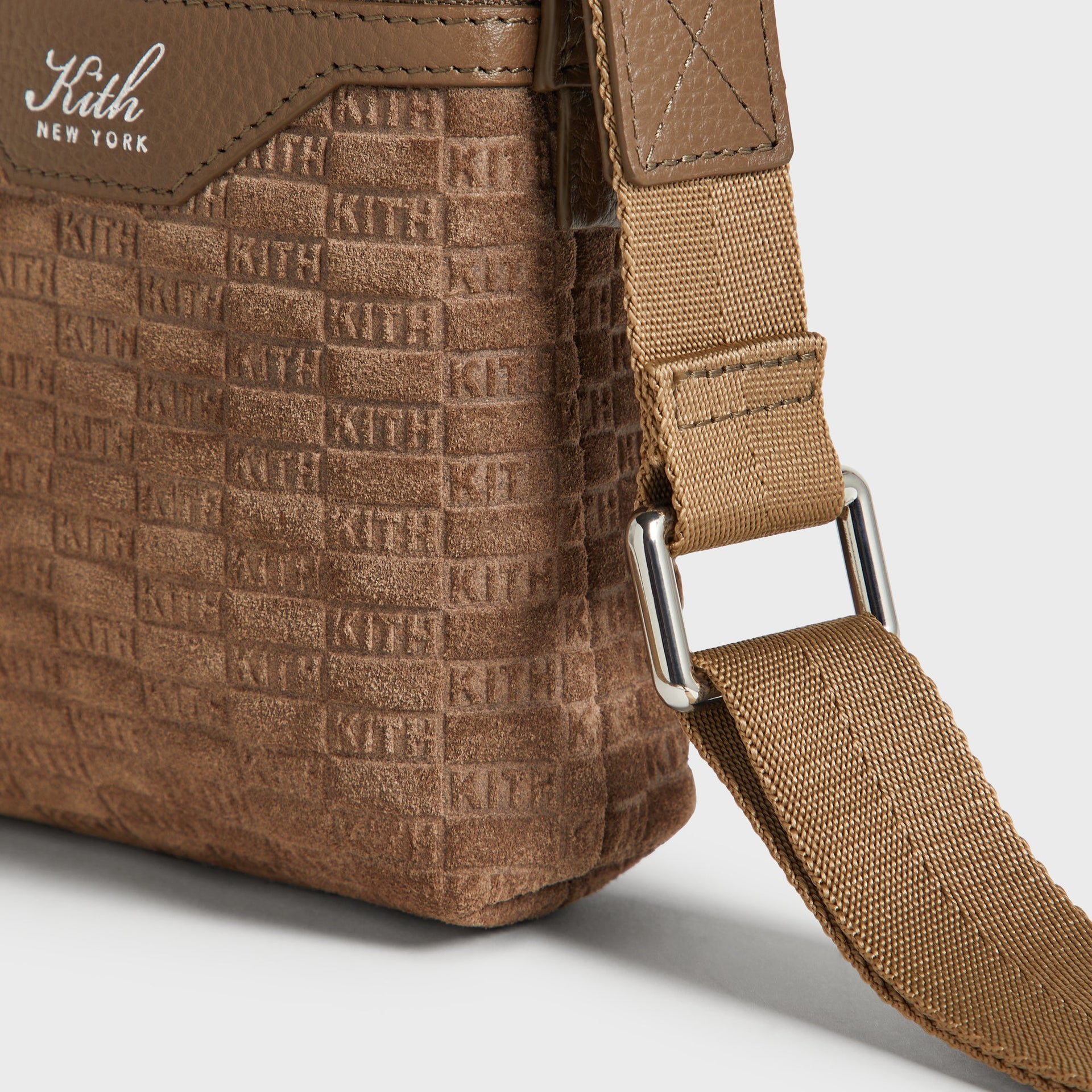 Angled side detail of the adjustable nylon strap buckle and suede corner on the Kith Drawstring Pouch