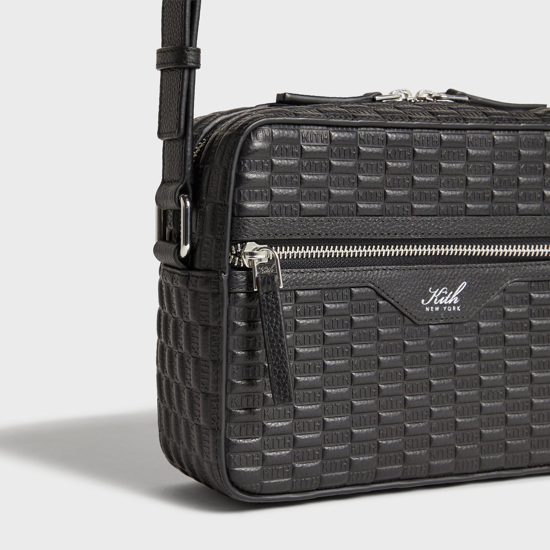 Close-up of corner strap clip and embossed KITH texture on Camera Crossbody Bag in Black leather