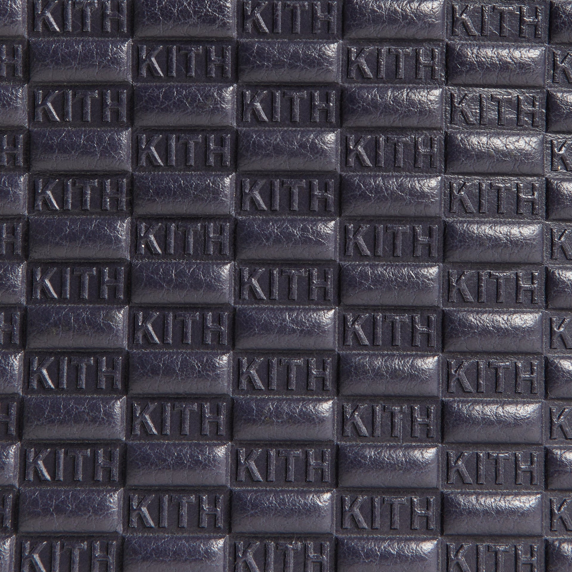Extreme close-up of the embossed Kith monogram pattern on tumbled leather, Passenger K15 Bag in Ink