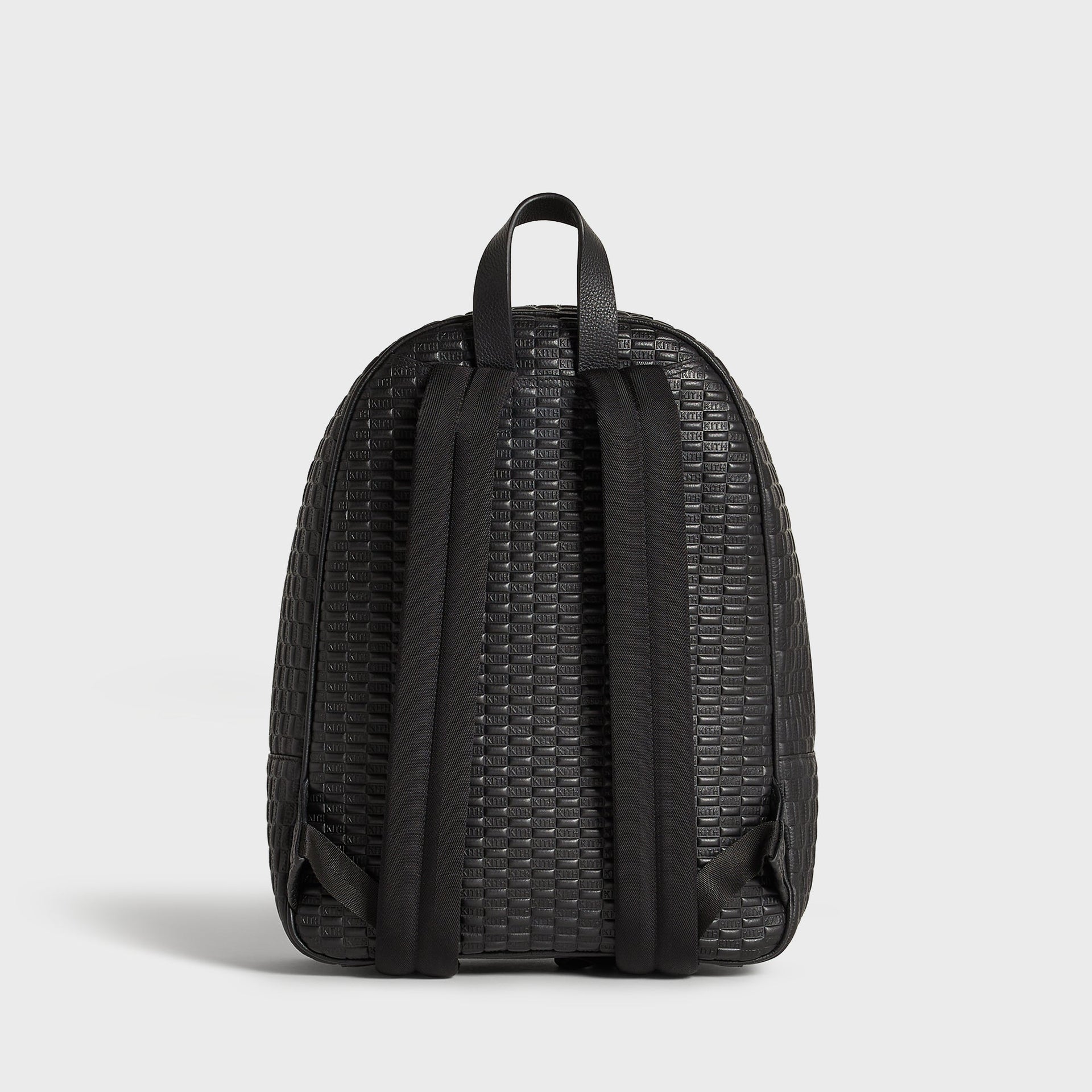 Kith Monogram Tumbled Leather Backpack in black, back view showing padded shoulder straps and top carry handle.
