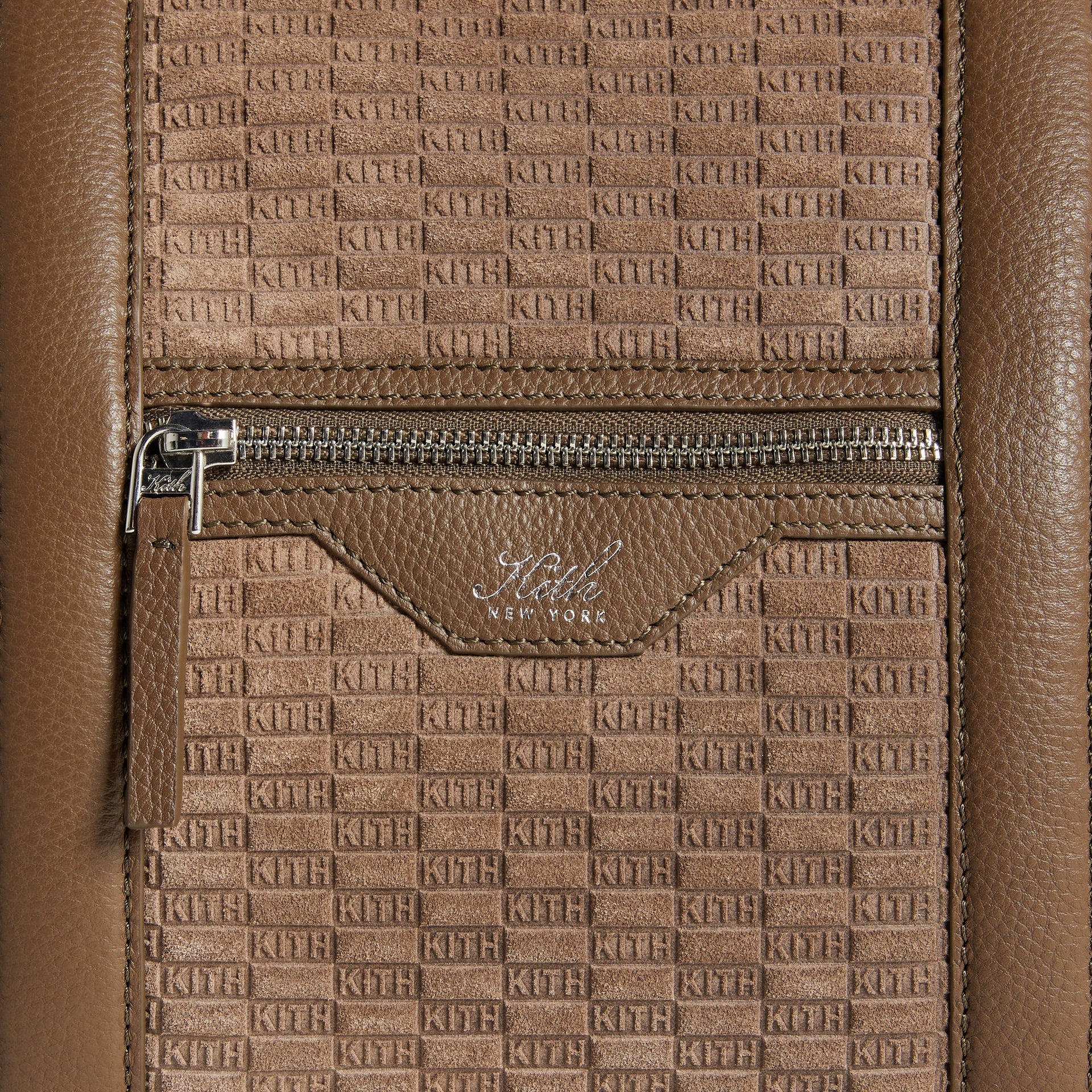 Close-up detail of front zip pocket with Kith New York leather tab on the Monogram Suede Traveler Duffle Bag