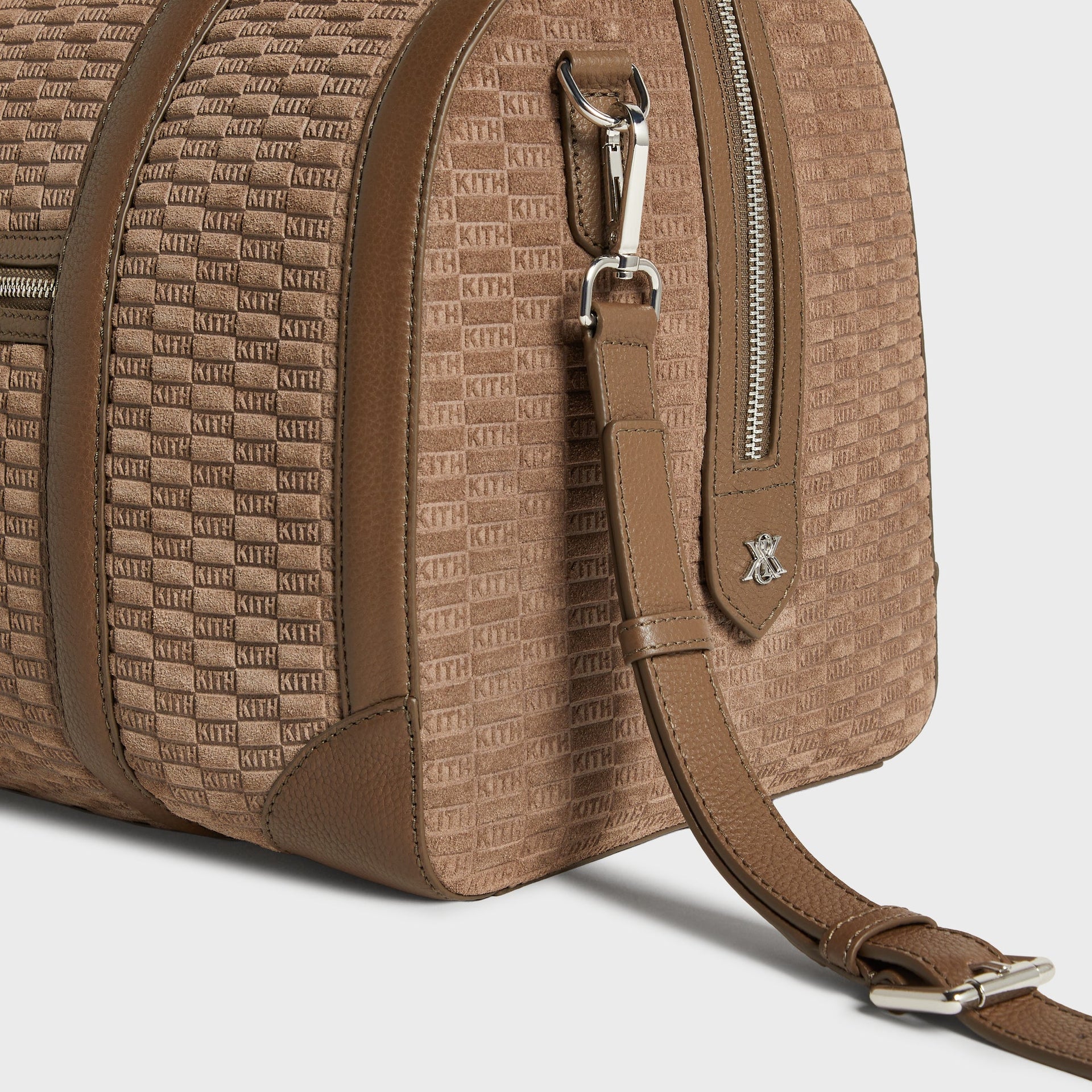 Close-up detail of corner leather trim and shoulder strap clasp on the Kith Monogram Suede Traveler Duffle Bag