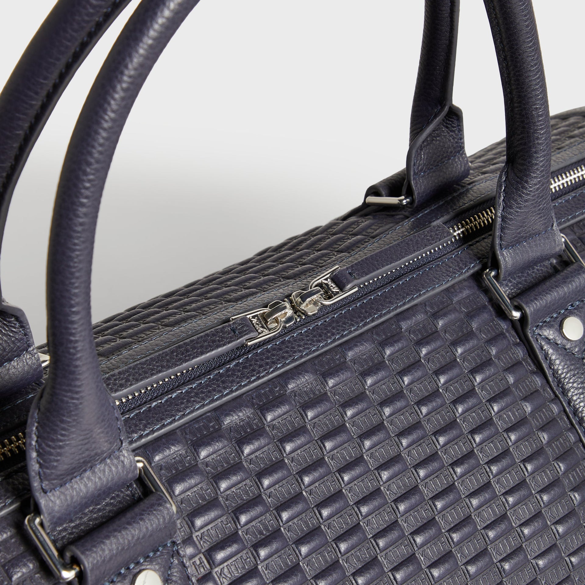 Close-up detail of leather handles and silver zipper pulls on Kith Monogram Traveler Duffle Bag in Ink