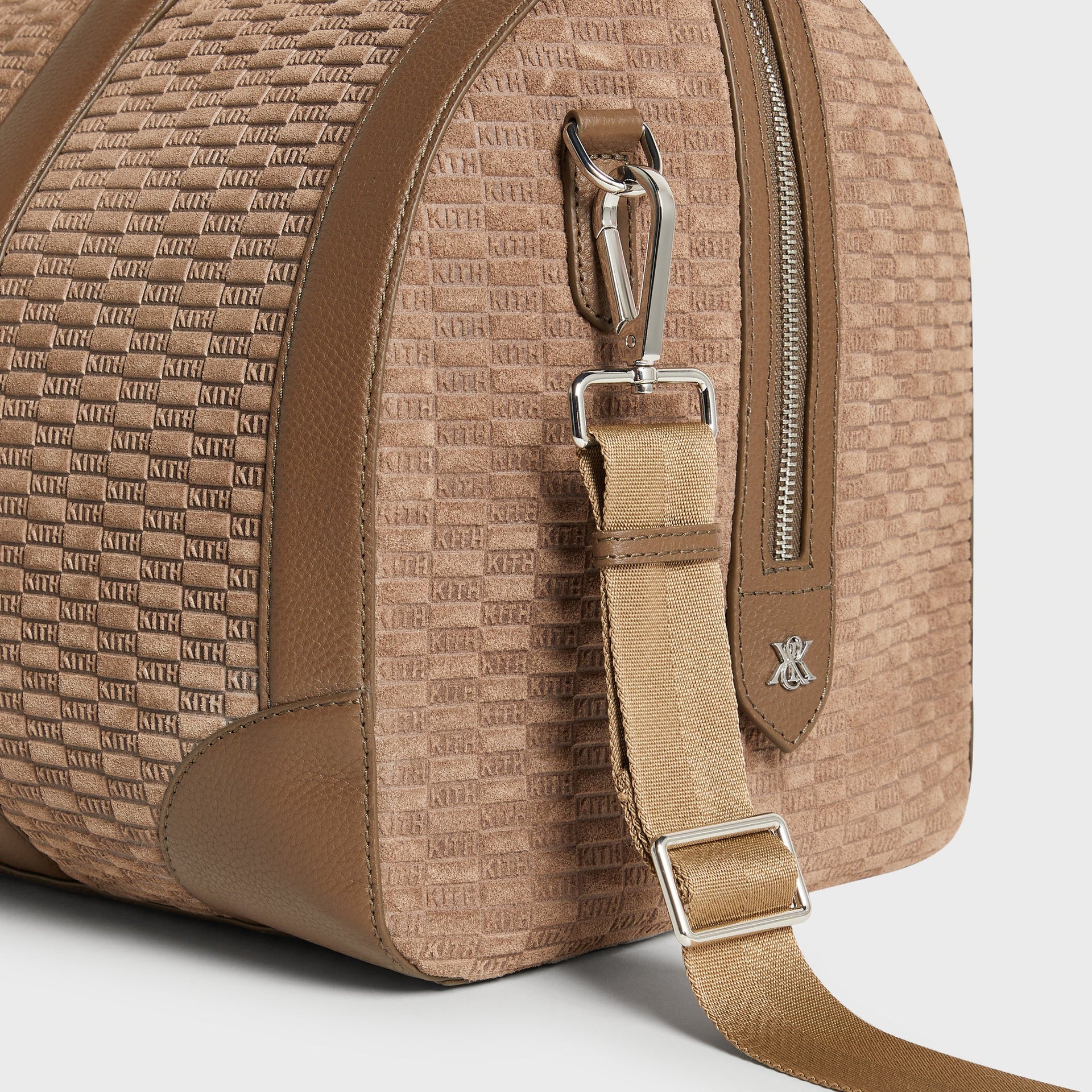 Detail of silver hardware, strap clip, and logo charm on the Kith Suede Traveler K55 Duffle Bag