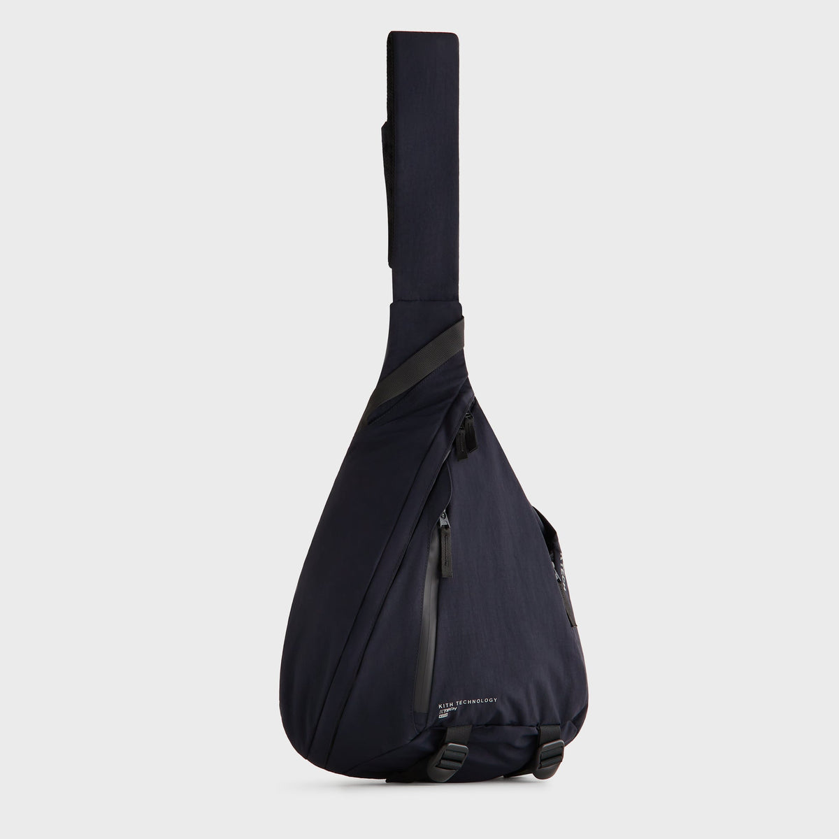 Kith Nylon Ripstop Sling Backpack in navy black, three-quarter view showing the teardrop silhouette and zip pockets
