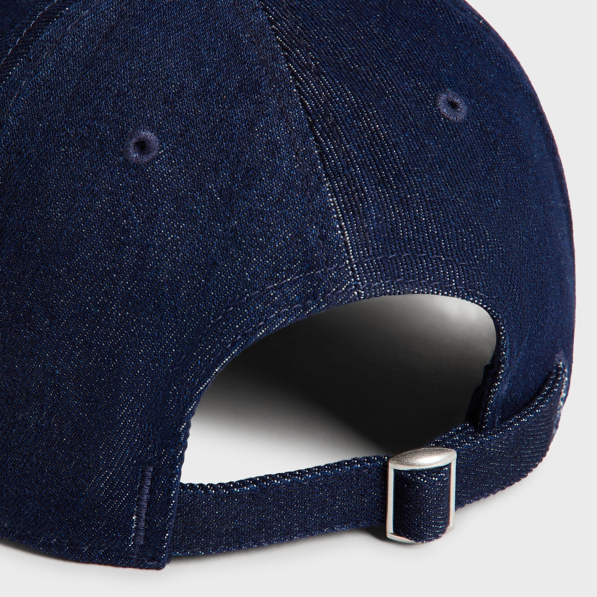 Close-up of the Kith Raw Denim Classic Cap's back strap eyelets and metal slide buckle in Savin Wash