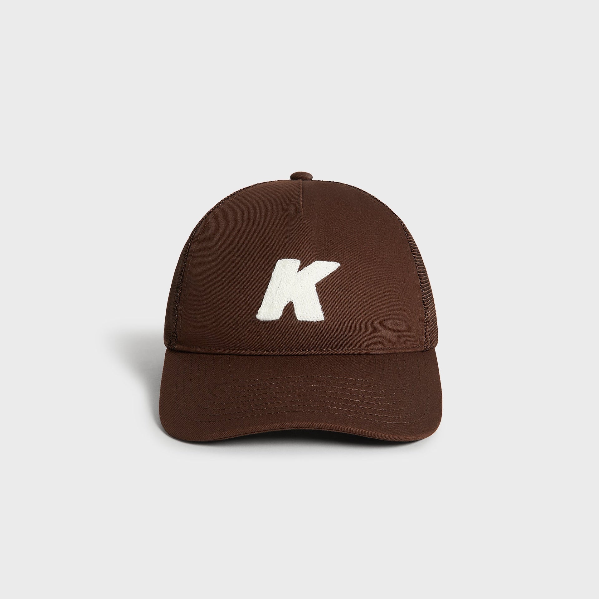 Kith Relaxed Twill Nolan Trucker Hat in Kindling brown, front view showing embroidered white K logo patch
