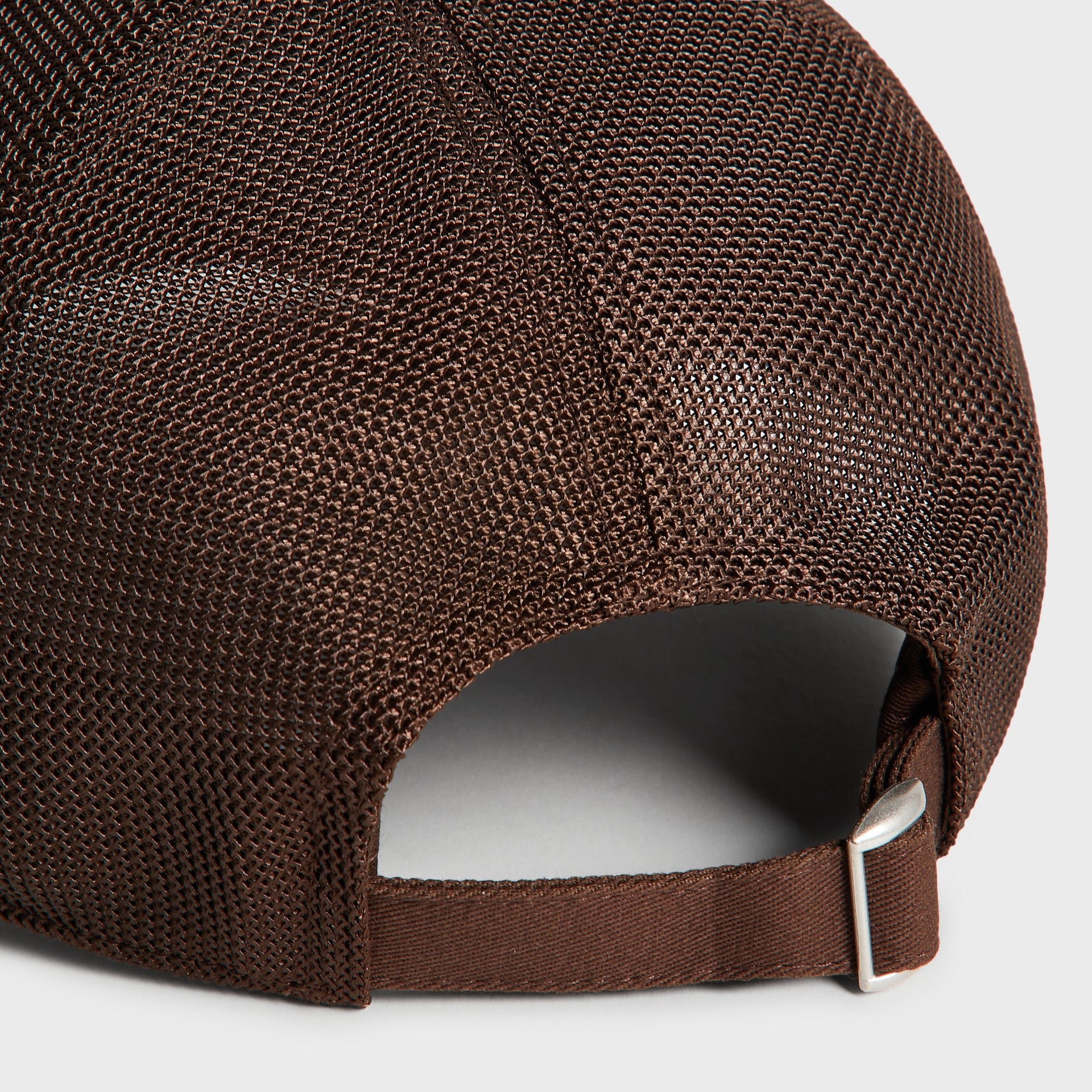 Close-up detail of brown mesh back panel and metal strap buckle on Kith Nolan Trucker Hat