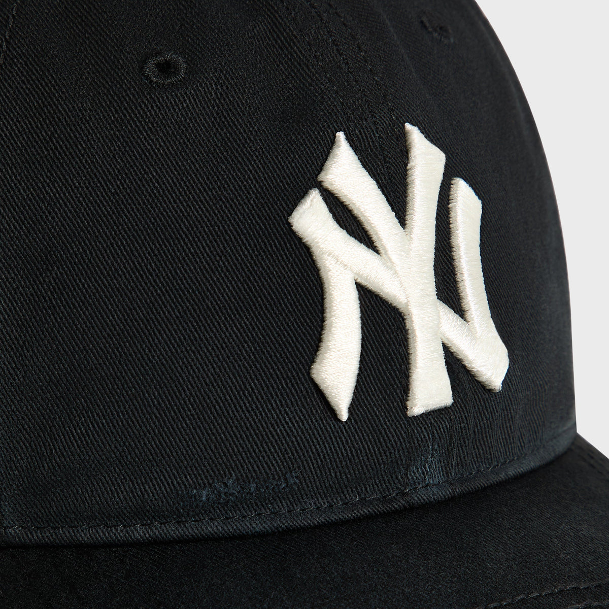Close-up of cream NY logo embroidery on Black Sun Faded Franchise LS Cap