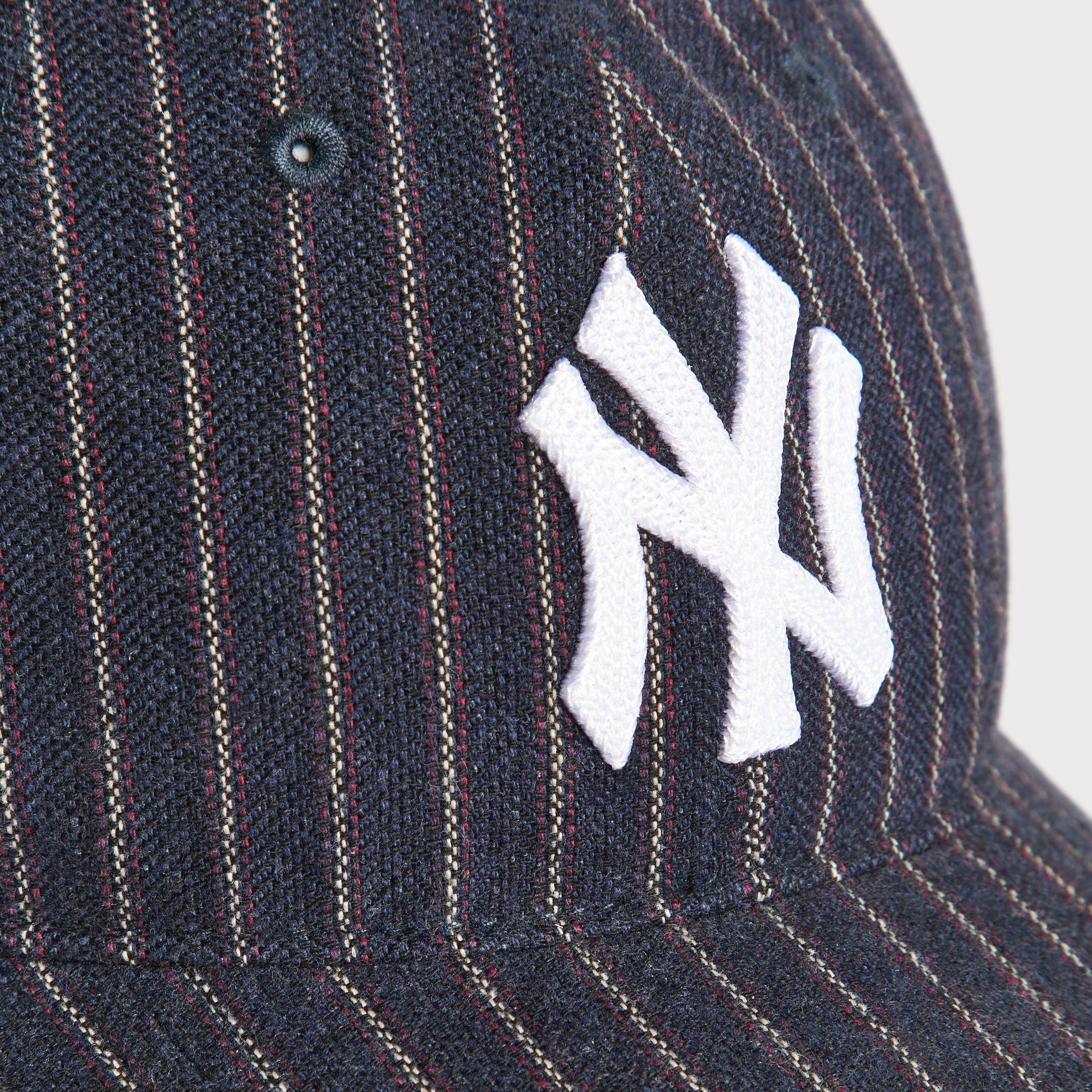 Close-up detail of embroidered white NY Yankees logo on Kith & '47 Barre Stripe cap pinstripe fabric