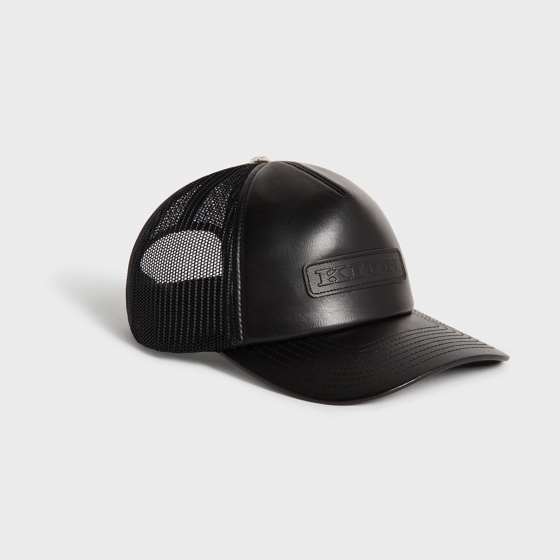 Kith Smooth Leather Nolan Trucker Hat in Black, three-quarter angle view of curved brim and mesh side