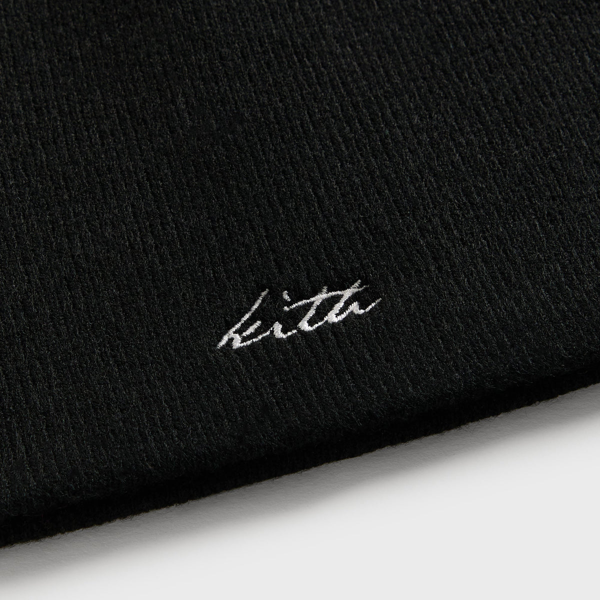 Close-up of white Kith script embroidery on black acrylic Cito beanie