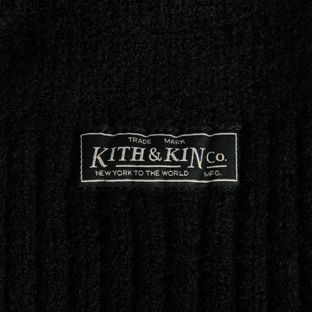 Close-up of Kith & Kin Co. woven label on black soft rib knit balaclava