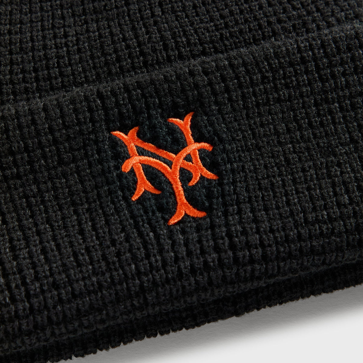 Close-up of orange embroidered NY Mets logo on black waffle knit Kith & '47 beanie cuff