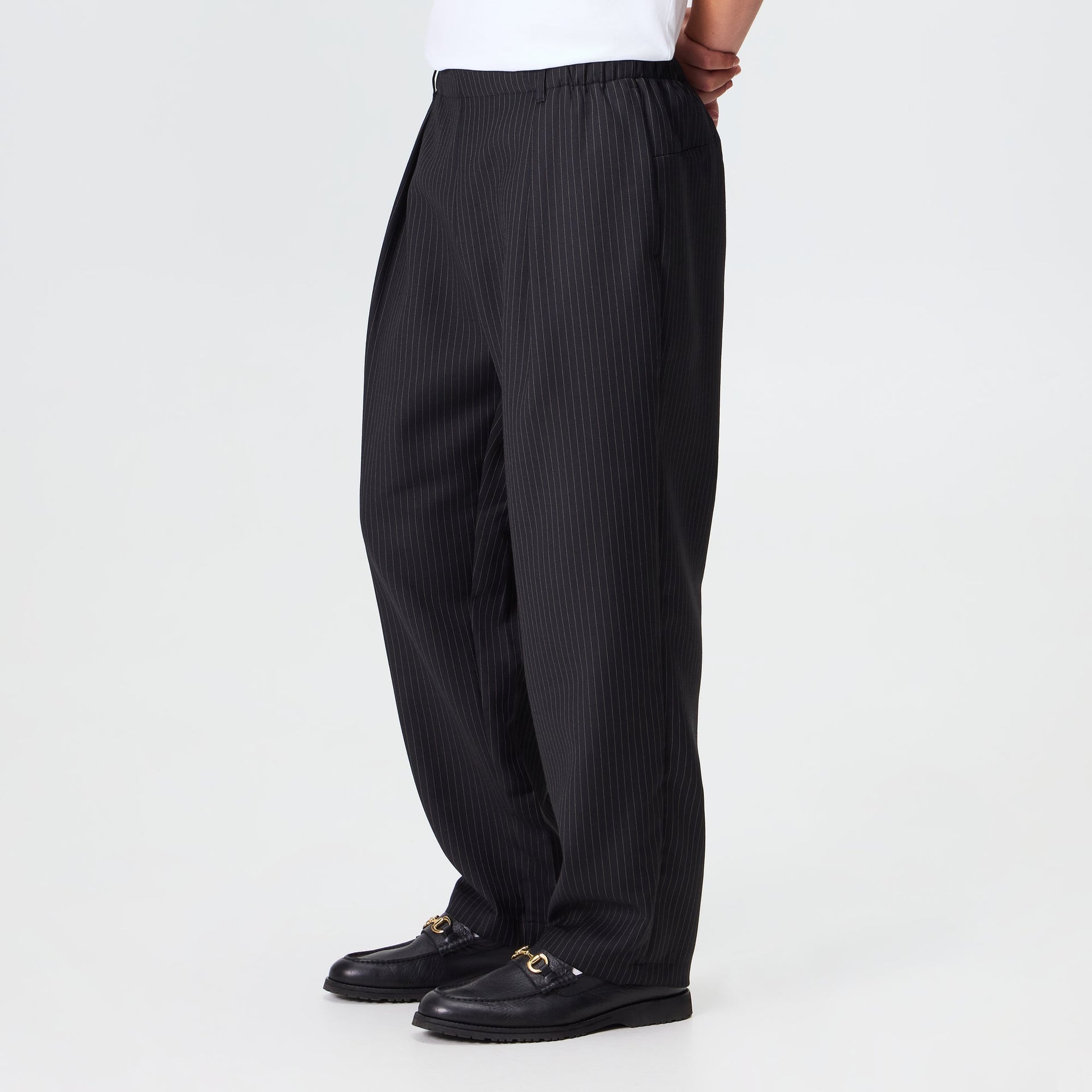 Man wearing the Kith Pinstripe Idris pant in black pinstripe with an elastic waist