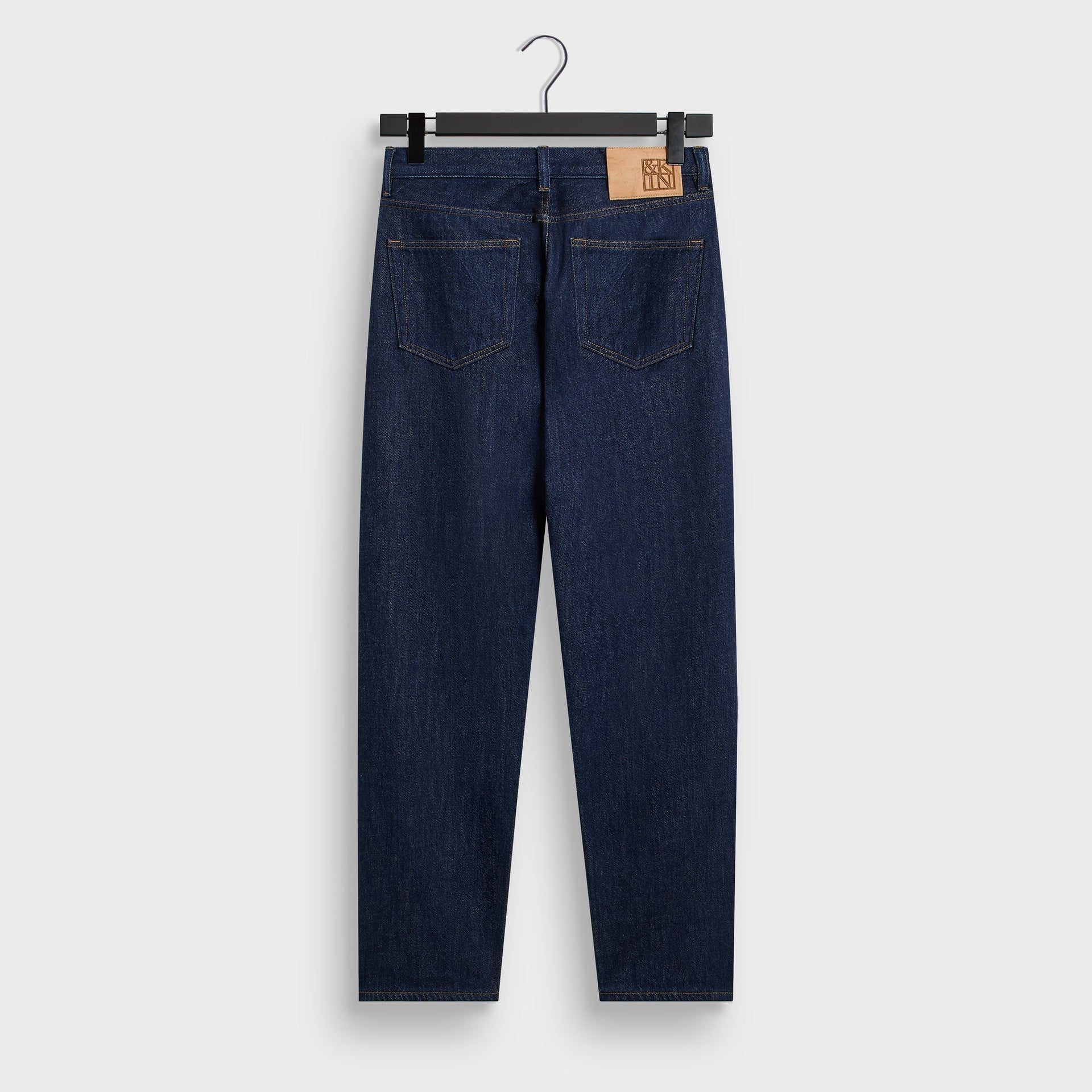 &Kin Webster Chill in Dark Indigo, back view on hanger with patch back pockets and tan leather waist patch