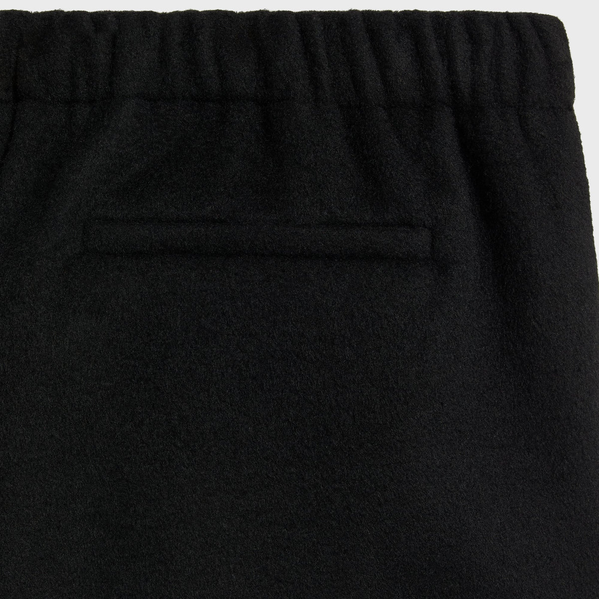 Close-up of the back welt pocket and elastic waistband on the black Avi wool pant