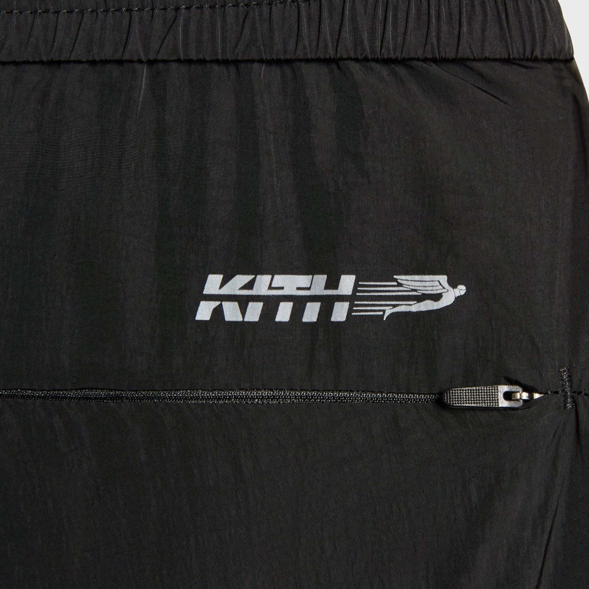 Close-up of the running figure Kith logo and zip pocket on the Nylon Bolt pant in black
