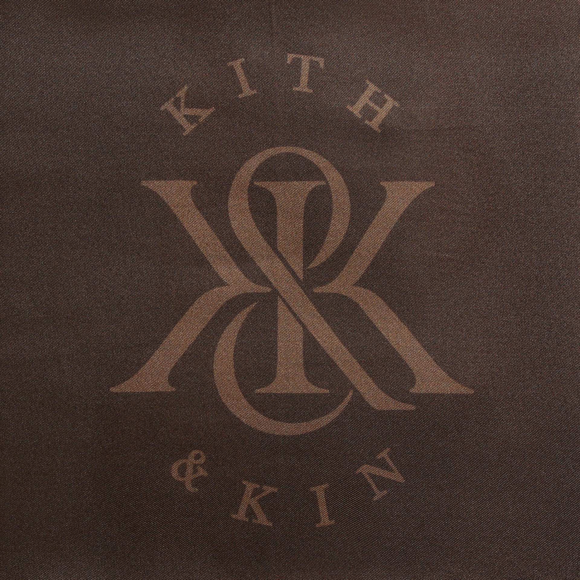 Close-up of Kith & Kin monogram logo print on Kith Printed Silk Rally Scarf in Auberge