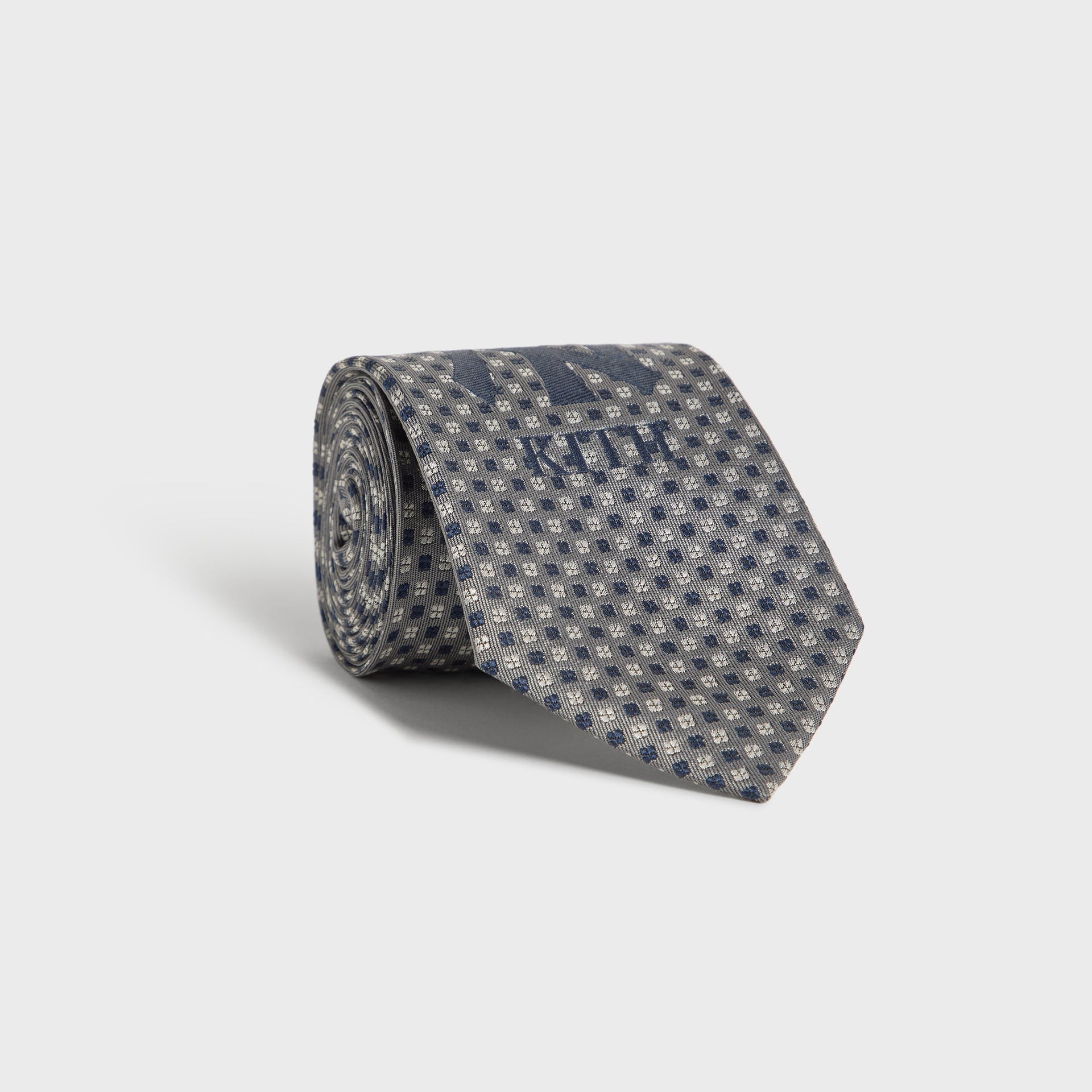 Kith x New York Yankees Skyscraper tie rolled up, showing grey dot pattern and NY logo