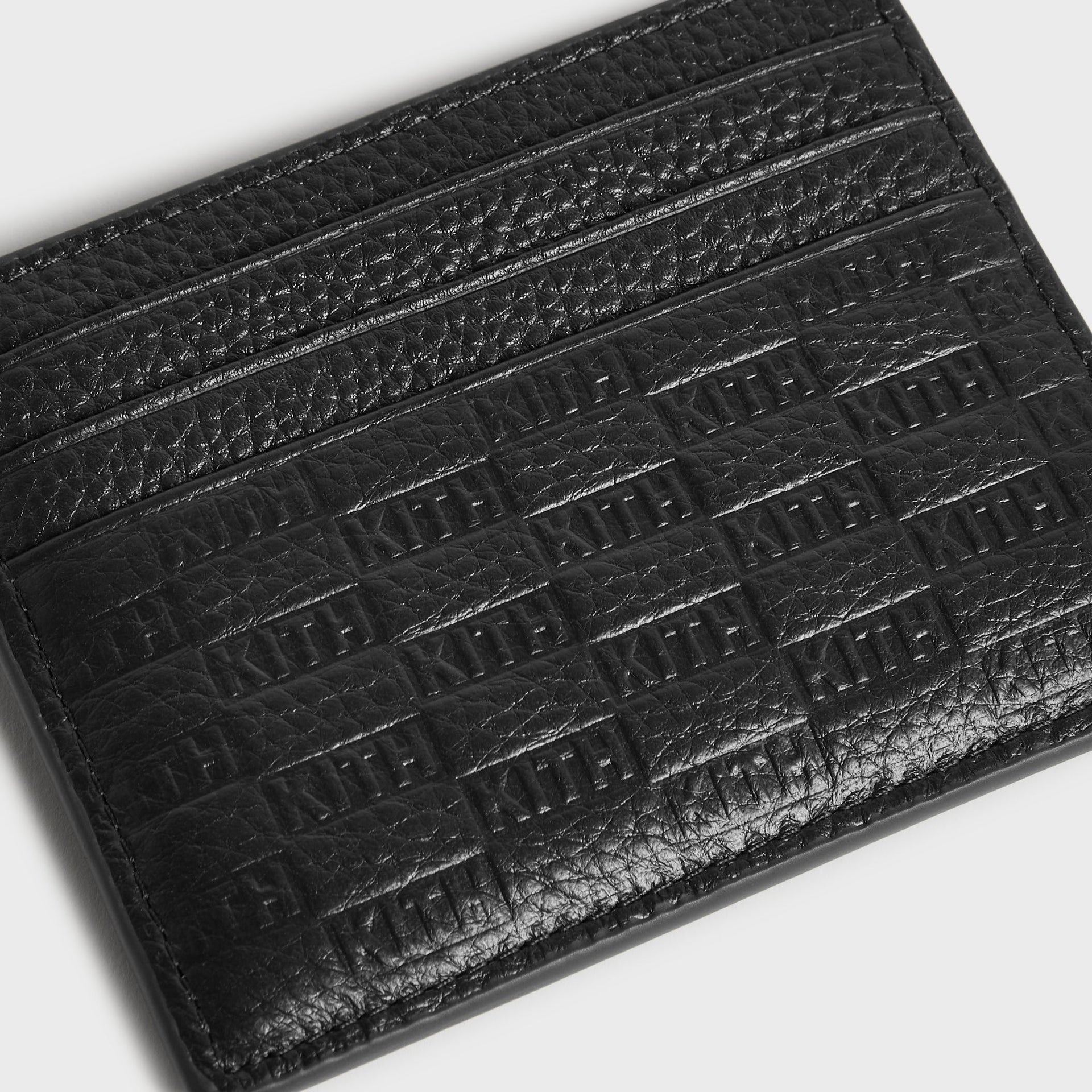 Close-up of the embossed Kith monogram pattern on the tumbled leather Card Holder in Black