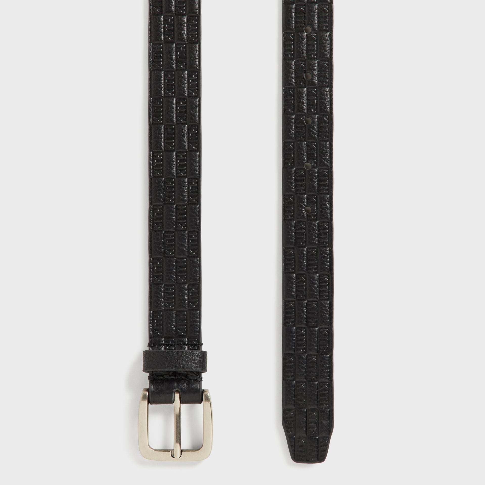 Kith Monogram Tumbled Leather Belt in Black, detail of buckle end and adjustment holes with embossed pattern