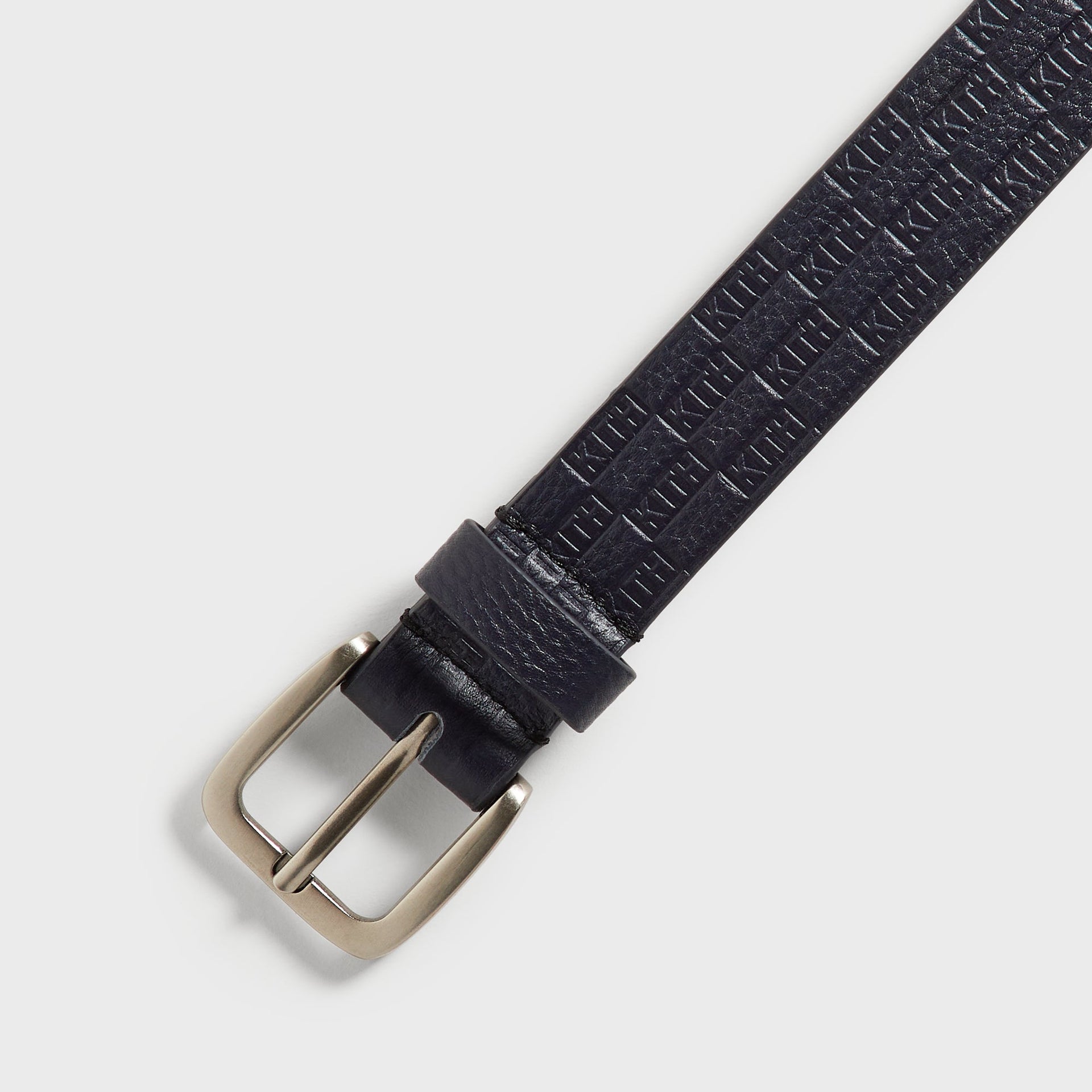 Kith Monogram Tumbled Leather Belt in Ink, close-up diagonal view of silver buckle and loop keeper
