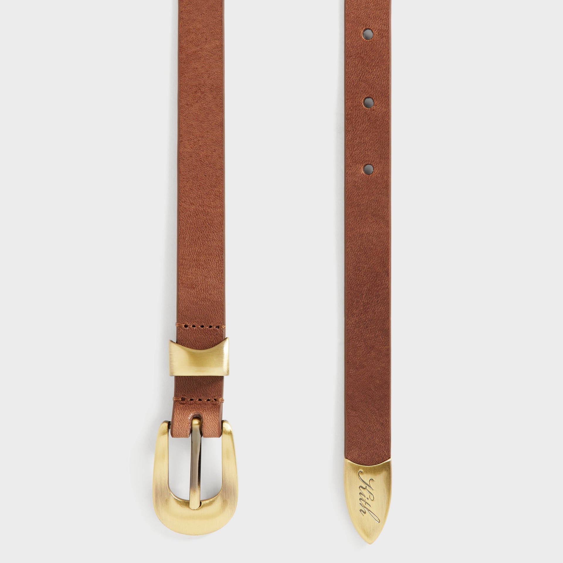 Detail of Kith Western Smooth Leather Belt showing brass keeper loop, punched holes, and gold-tipped strap end