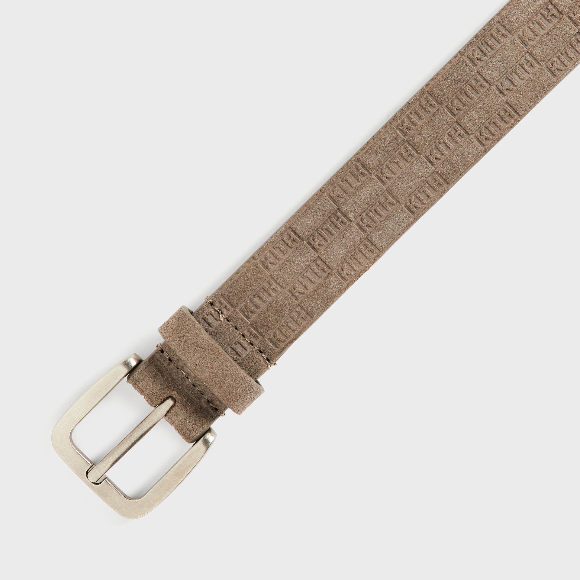 Kith Monogram Suede Belt in Java, diagonal close-up of the buckle and strap showing embossed KITH monogram pattern