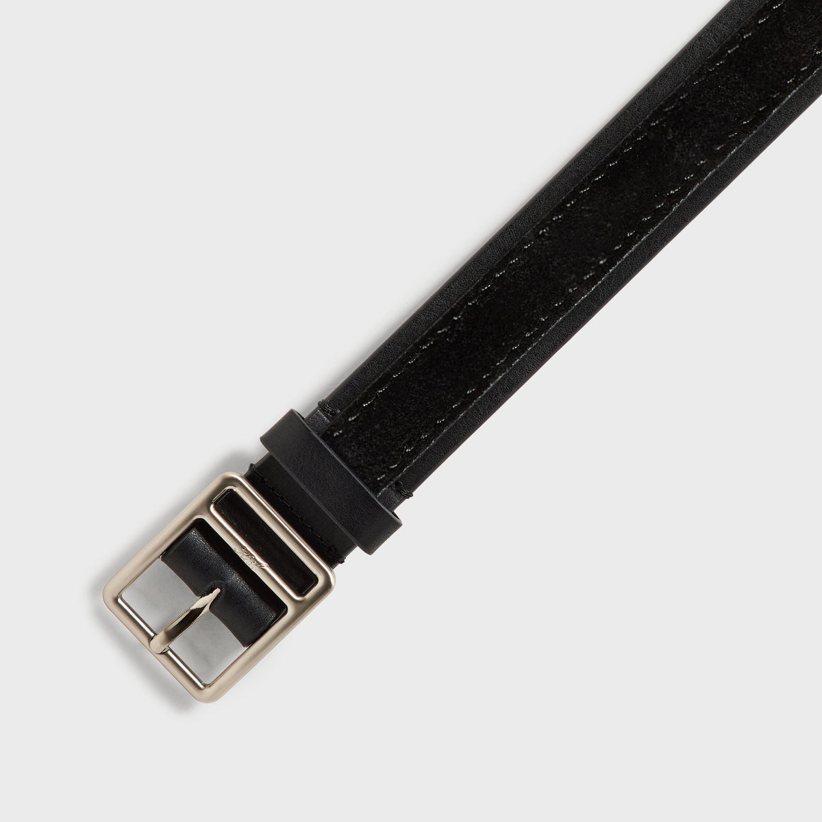 Close-up of silver buckle on black two-tone smooth leather and suede Kith belt