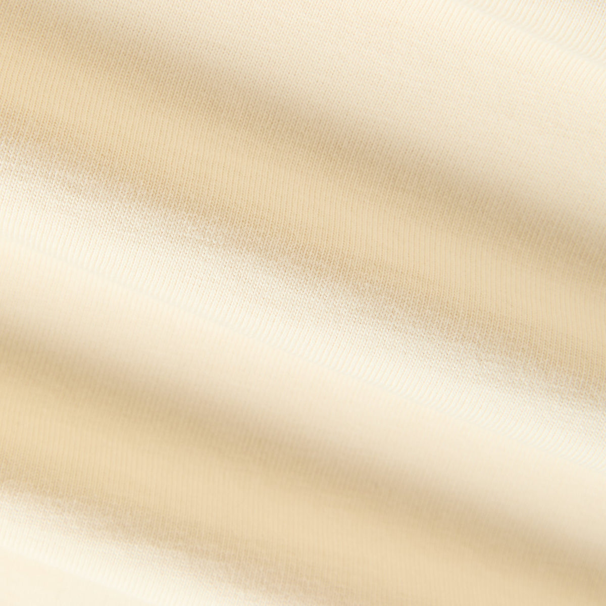 Close-up of cream cotton jersey fabric texture on the script Alex tee