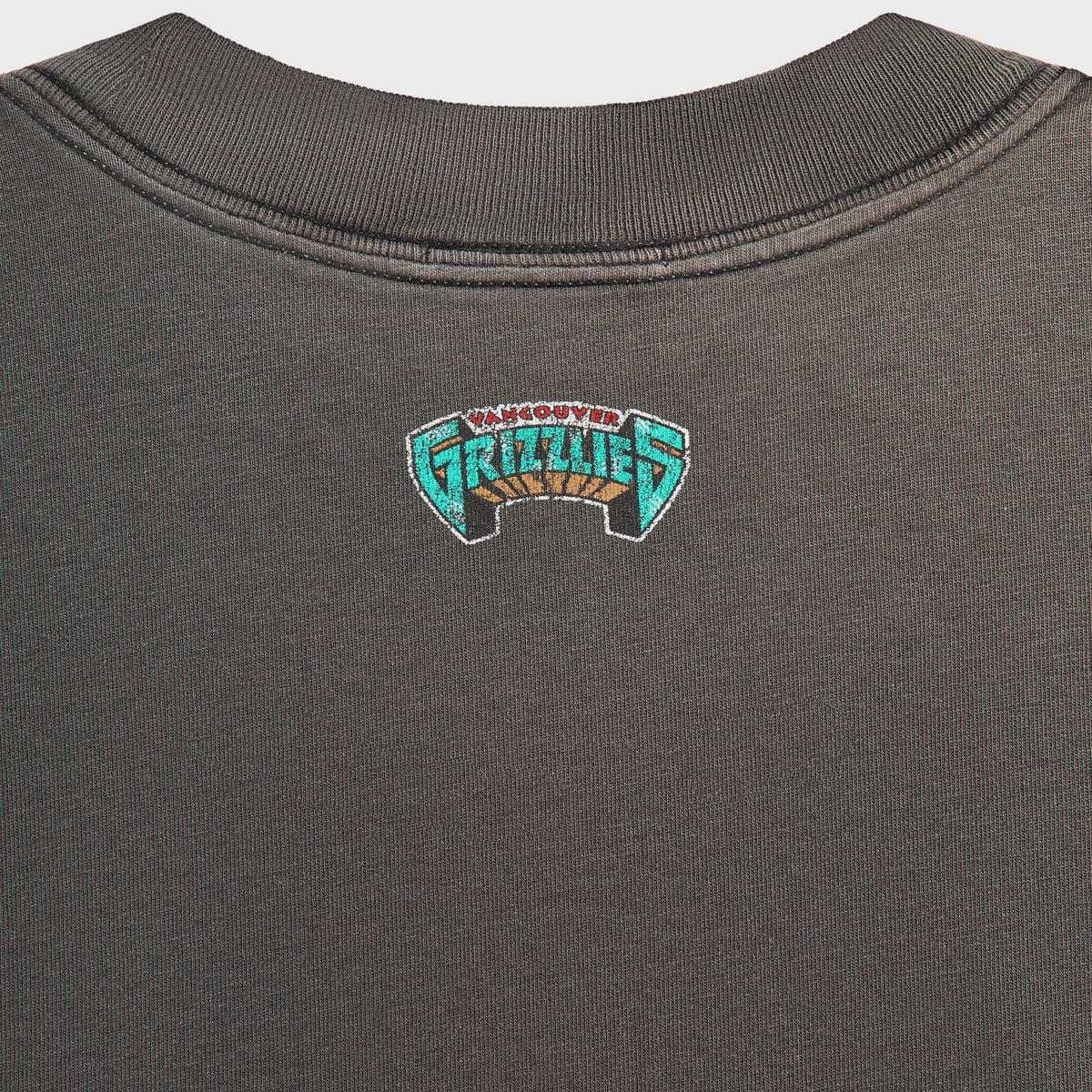 Kith for the Vancouver Grizzlies Vintage Jones II Tee close-up of small teal Grizzlies logo at the back neck on washed black