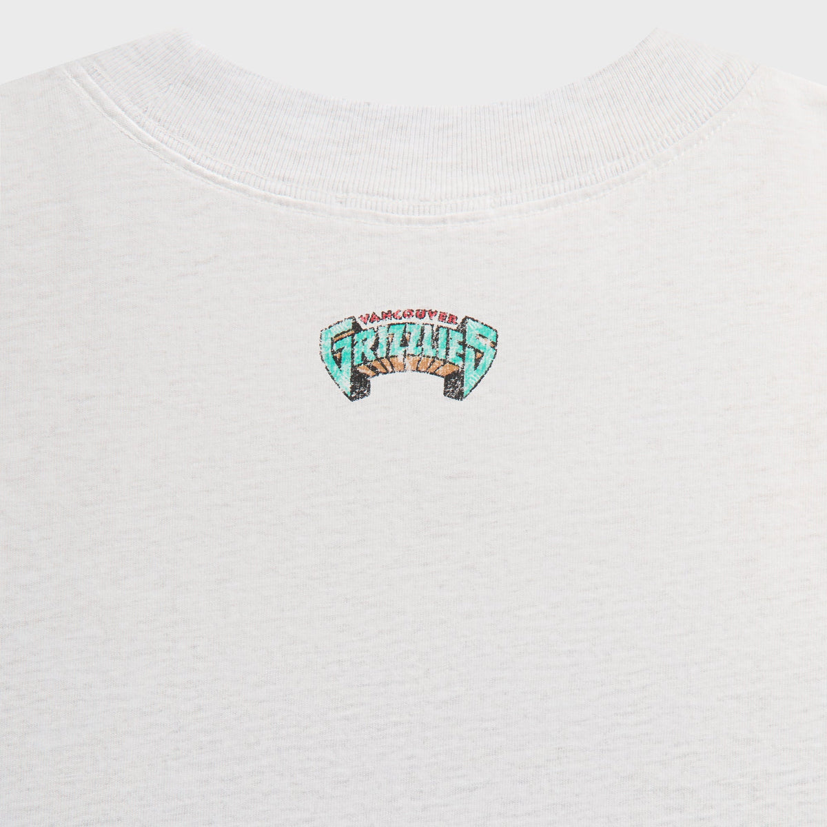 Close-up of small Grizzlies logo below the back collar of the light heather grey Kith Vintage Jones II tee