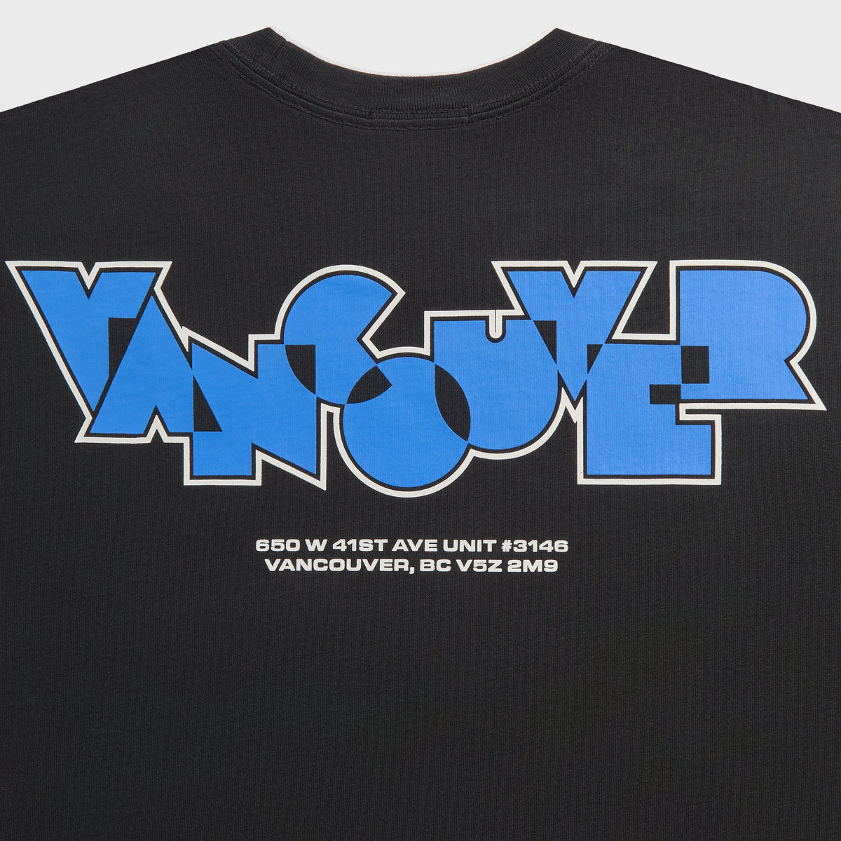 Close-up of blue Vancouver block-letter graphic with address text on the back of the black Kith long sleeve tee