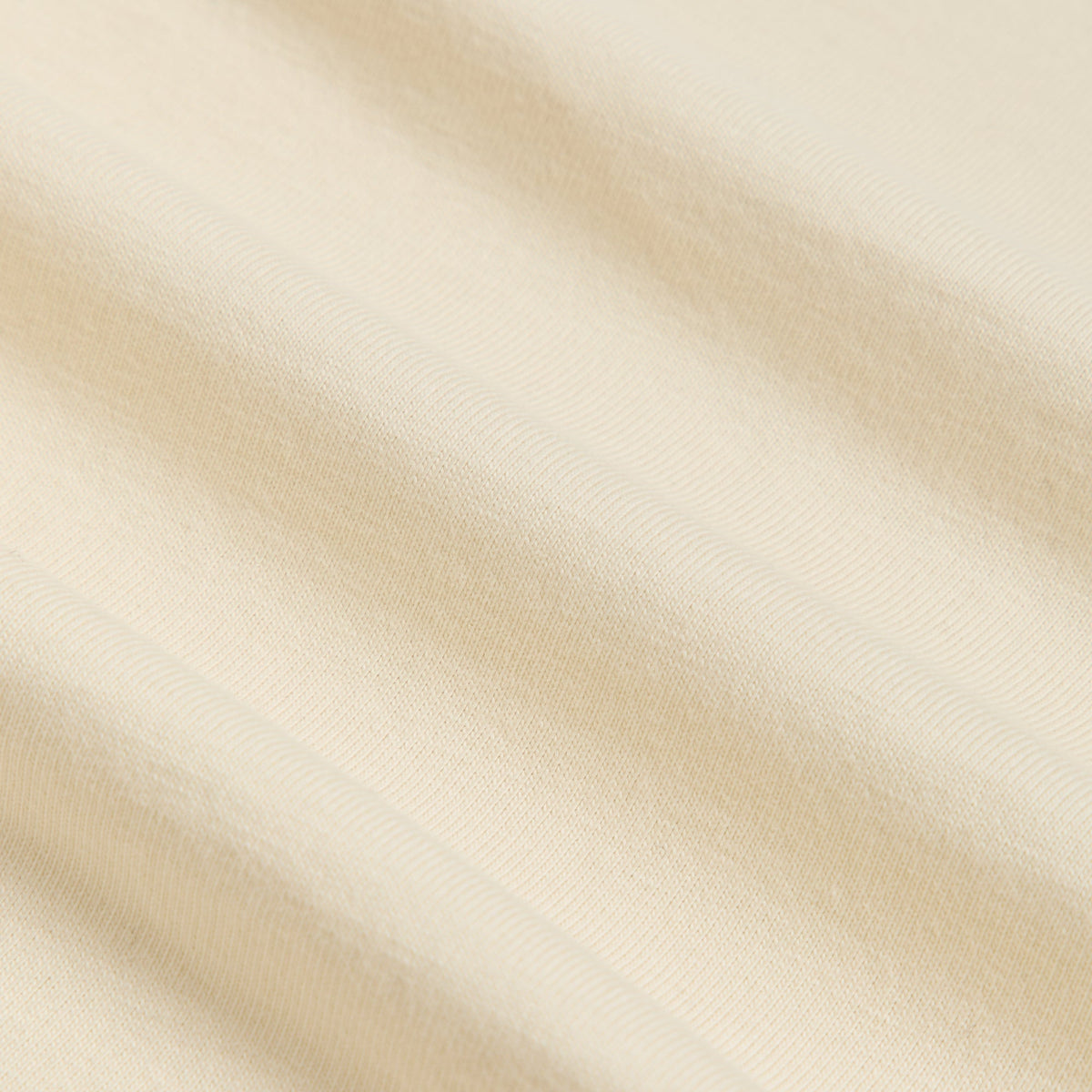 Fabric detail of Kith Treats Pumpkin Harvest Pocket Tee in Sandrift, soft cream ribbed cotton jersey texture