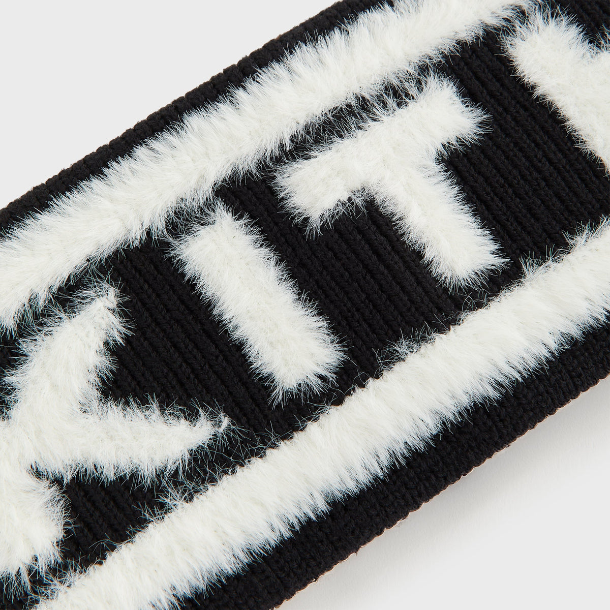 Macro close-up of the black Kith Jacquard Rib Headband's white fuzzy 'KITH' knit lettering texture
