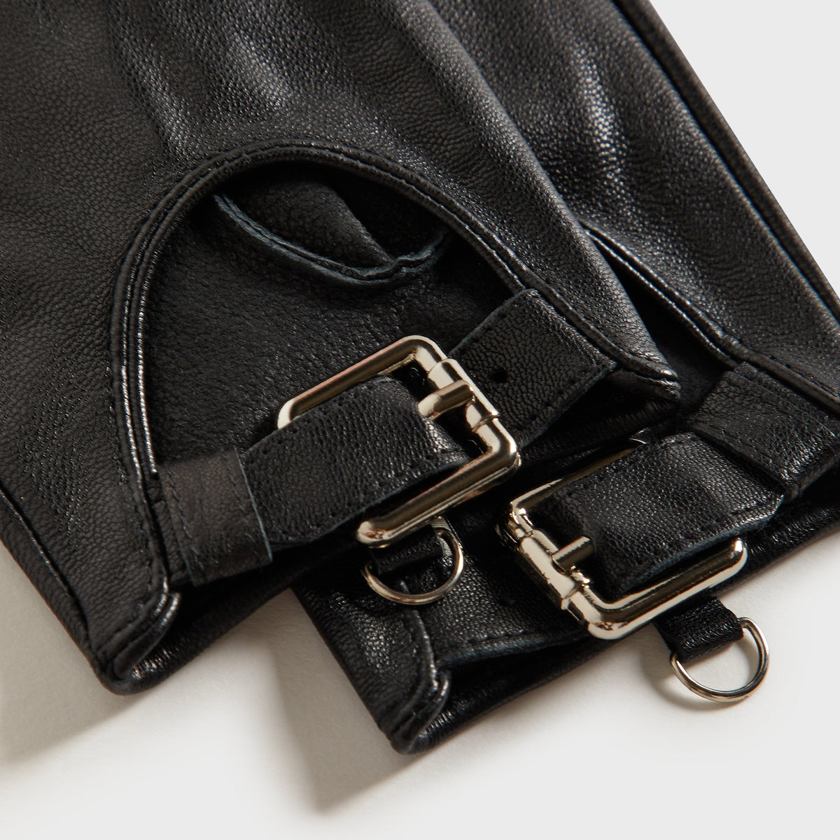Close-up of the silver buckle and D-ring hardware on the Kith cut-out fitted gloves in black leather