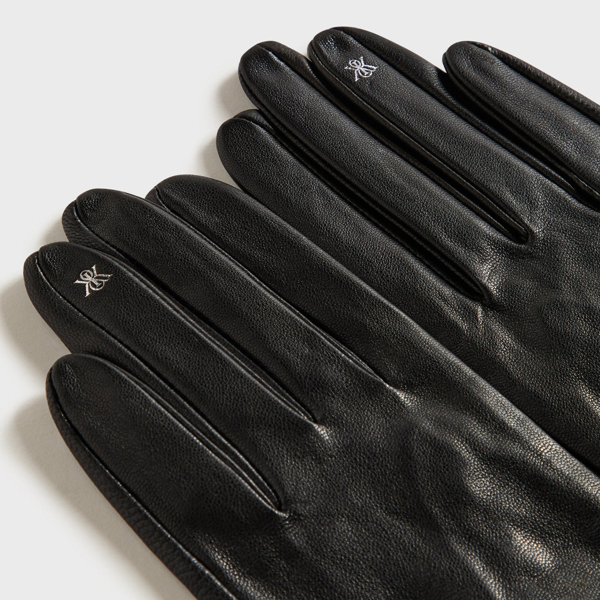 Close-up of the embroidered logo on the fingertips of the Kith Women cut-out fitted gloves