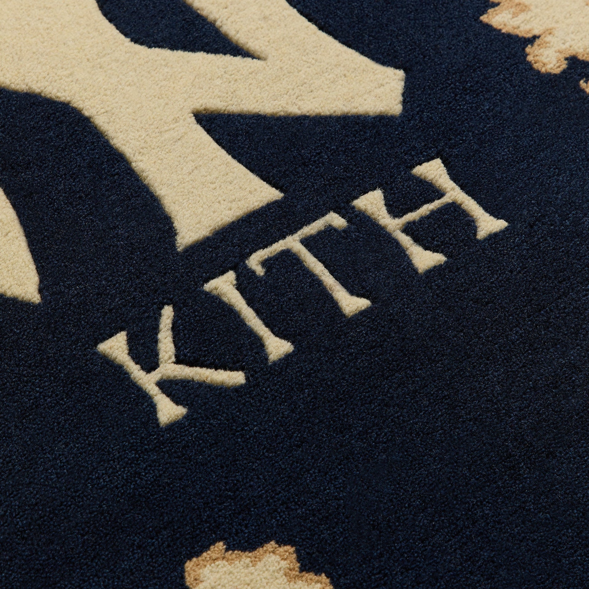 Close-up of Kith lettering detail woven into the hand-knotted rug border pattern