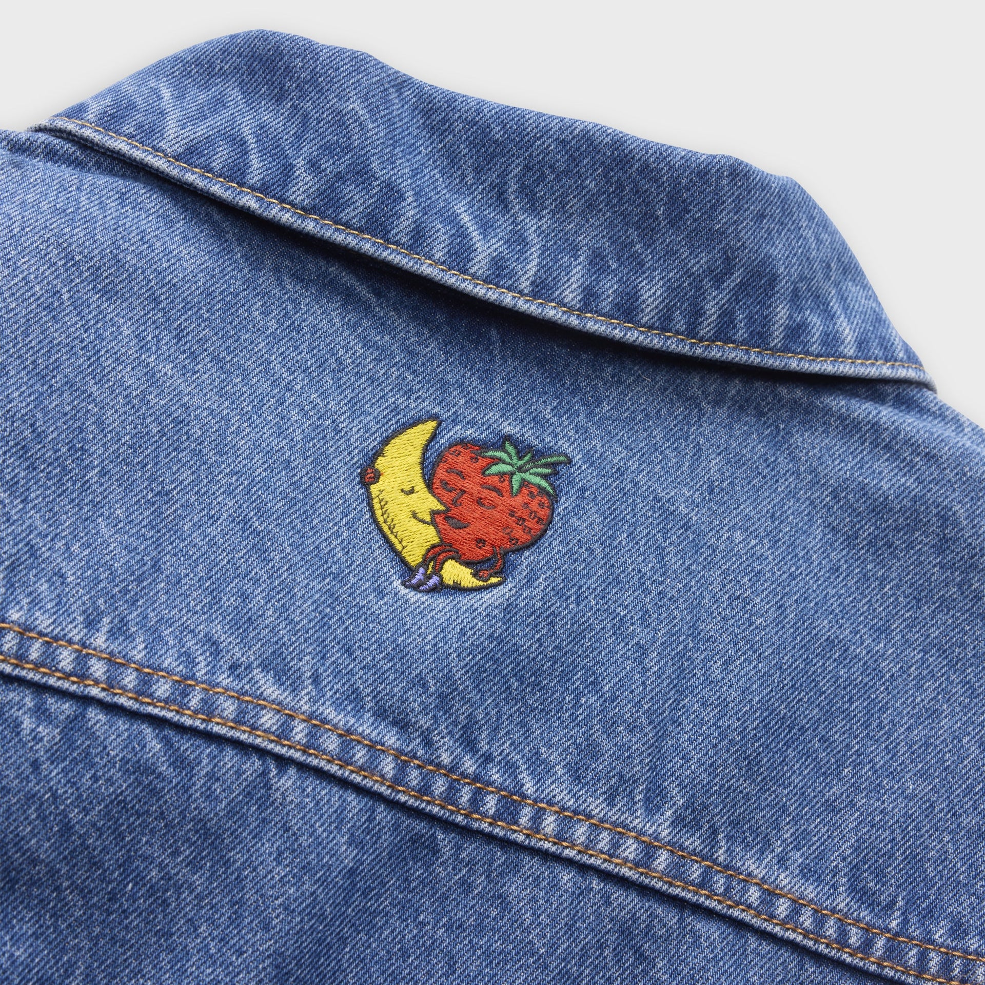 Close-up of Levi's x Sky High Farm washed-blue trucker jacket back collar with embroidered moon-and-strawberry mascot