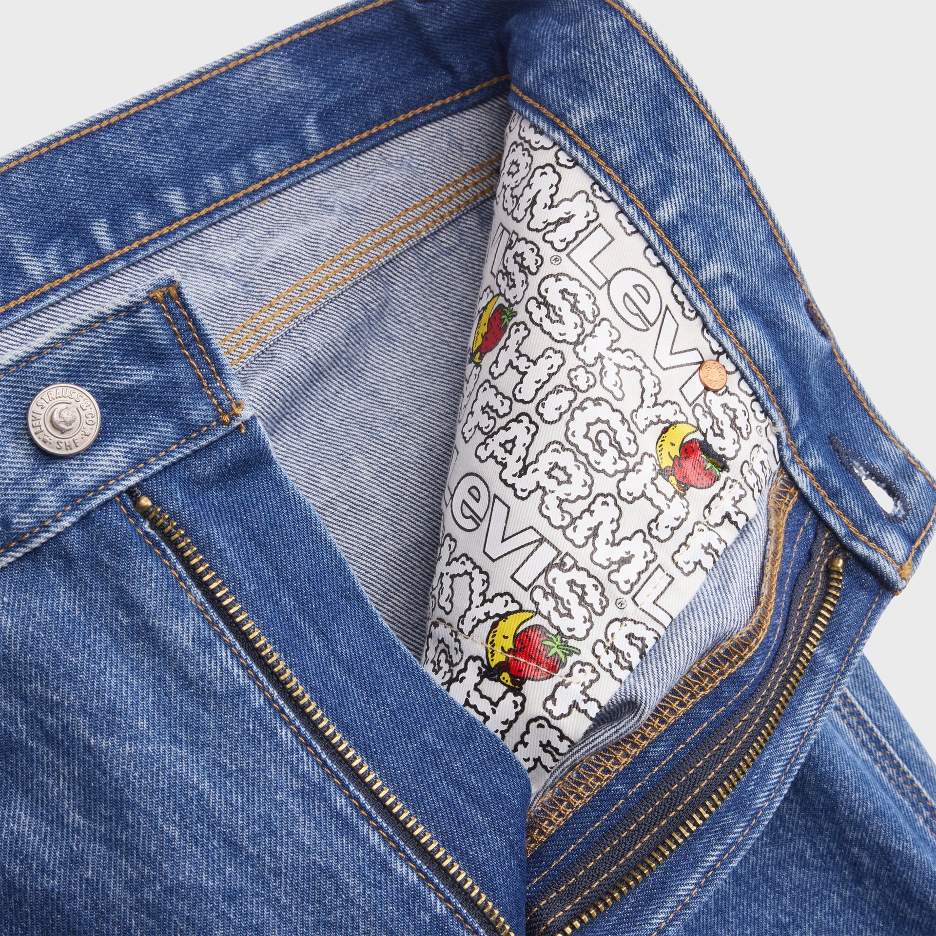 Interior fly of Levi's x Sky High Farm shorts showing button, zipper and white pocket lining printed with the collab logo