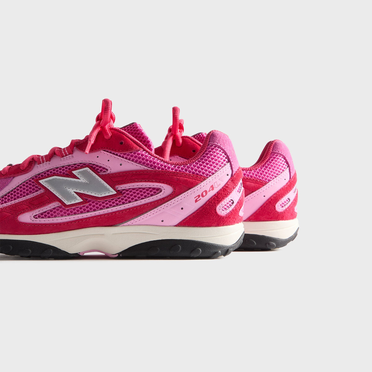 Kith & New Balance 204L in Camellia, angled rear-side view of the pair showing 204 branding and red suede heels