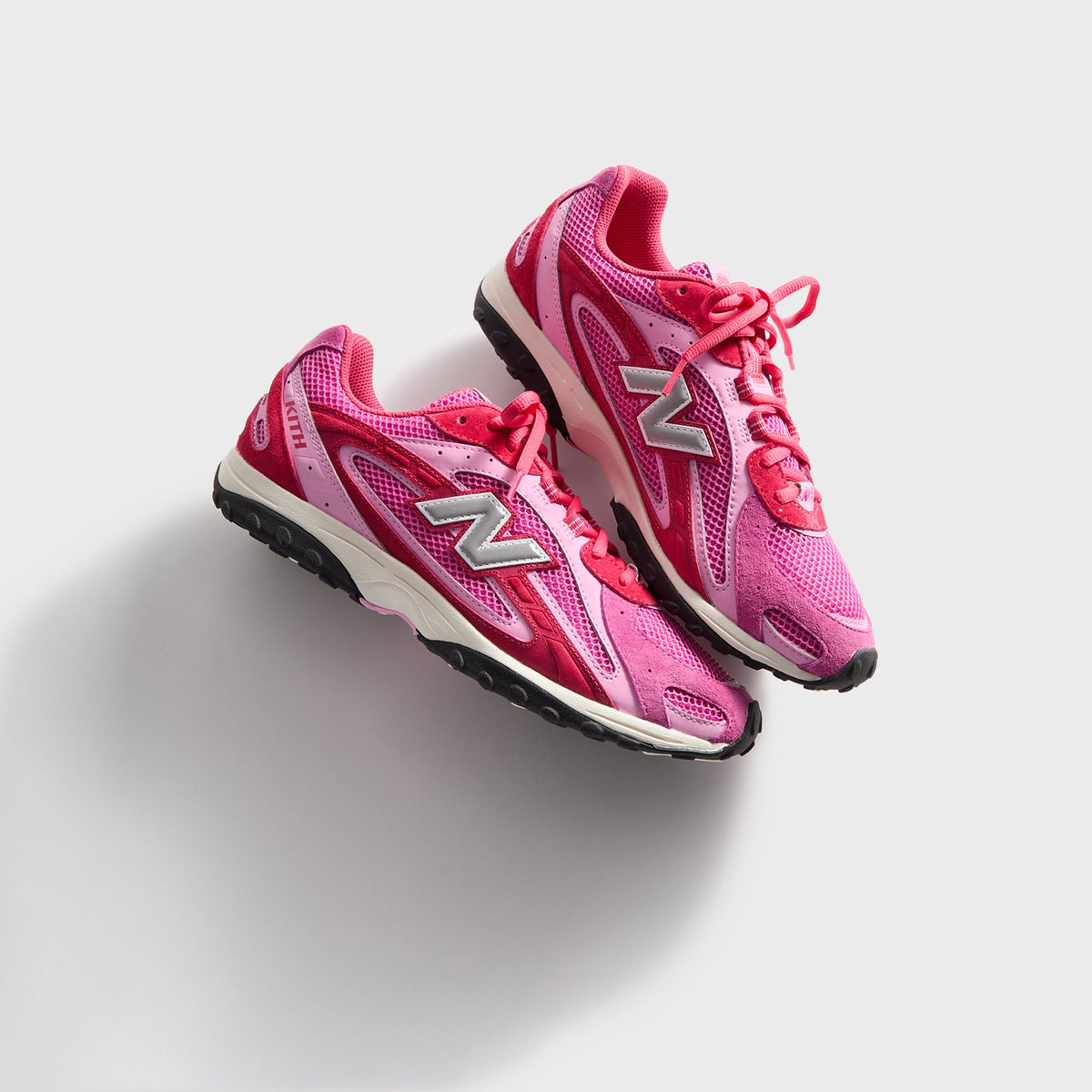 Kith & New Balance 204L in Camellia, overhead angled view of the pink pair with red laces and silver N logos up