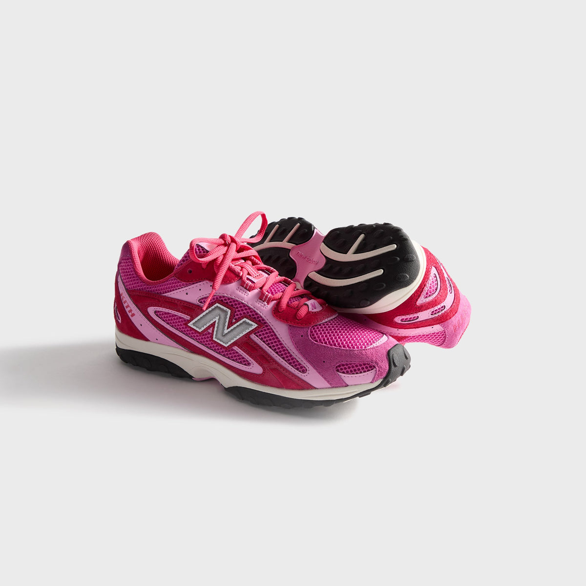 Kith & New Balance 204L in Camellia, pair with one sneaker upright and one on its side showing the outsole